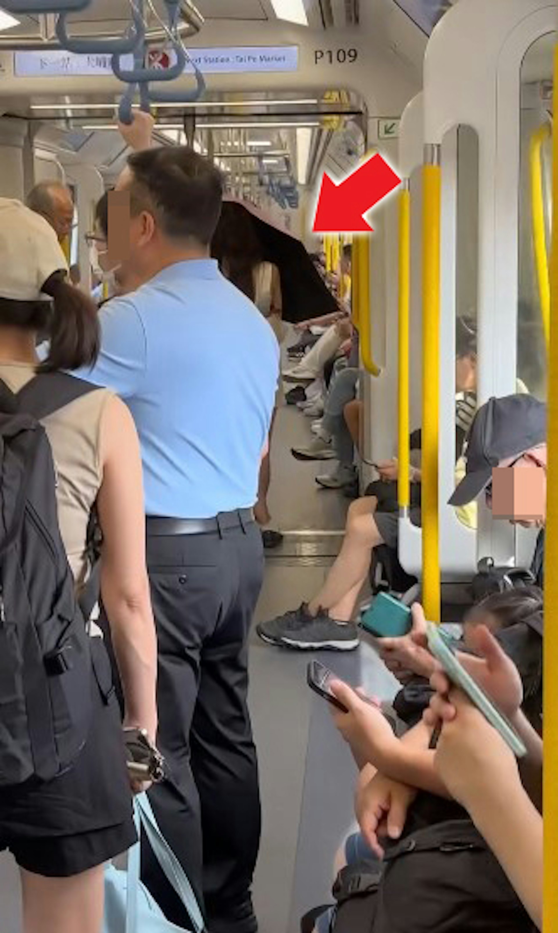 1名長頭髮、身穿無袖連身裙的女乘客搭乘港鐵時,於車廂內打開縮骨遮,擋着自己正前方。(threads影片截圖)
