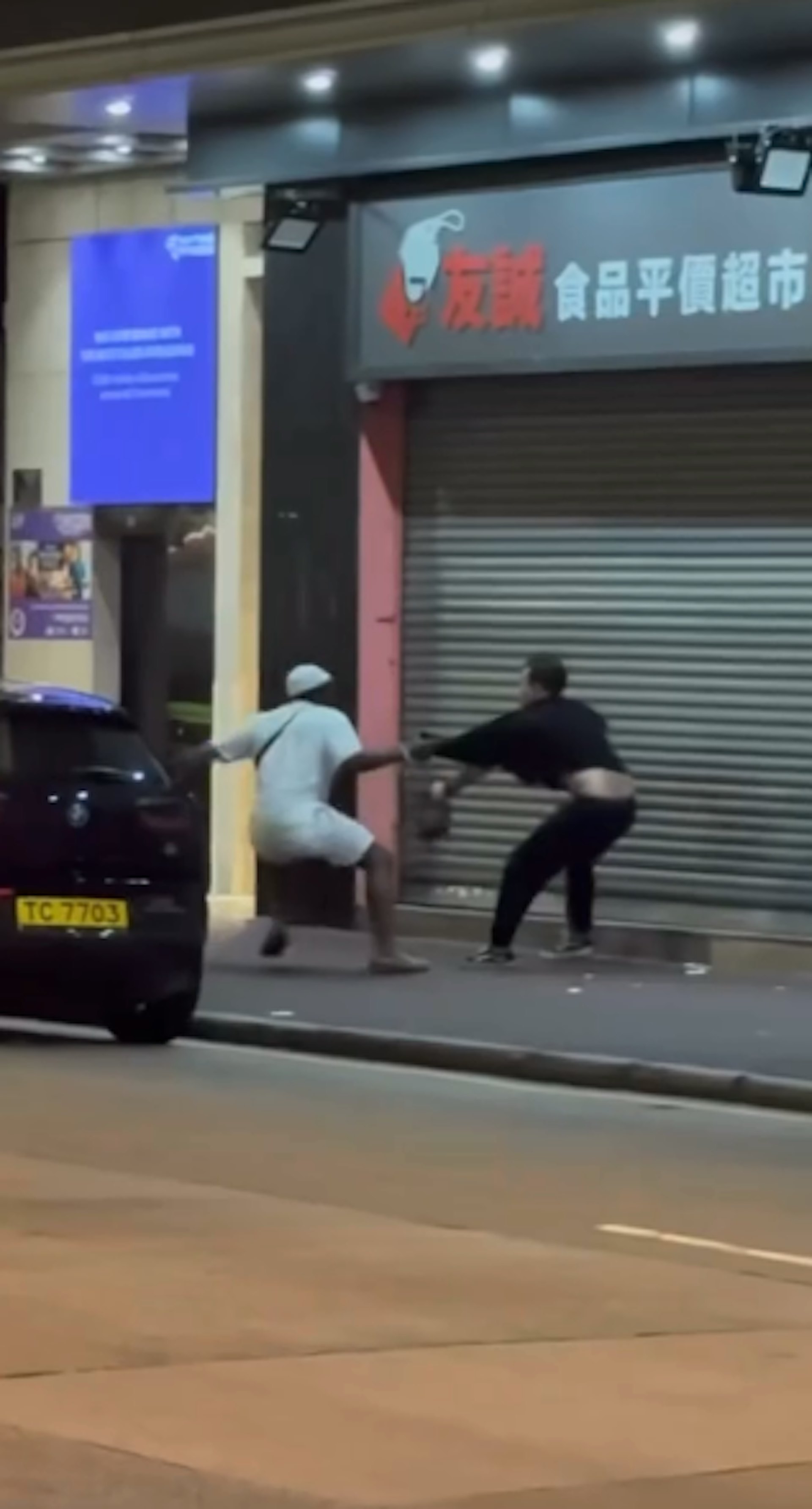 網上流傳一條5秒片段,可見一名非裔男子與一名黑衣男,在長沙灣青山道一間超市外糾纏。(網上影片截圖)