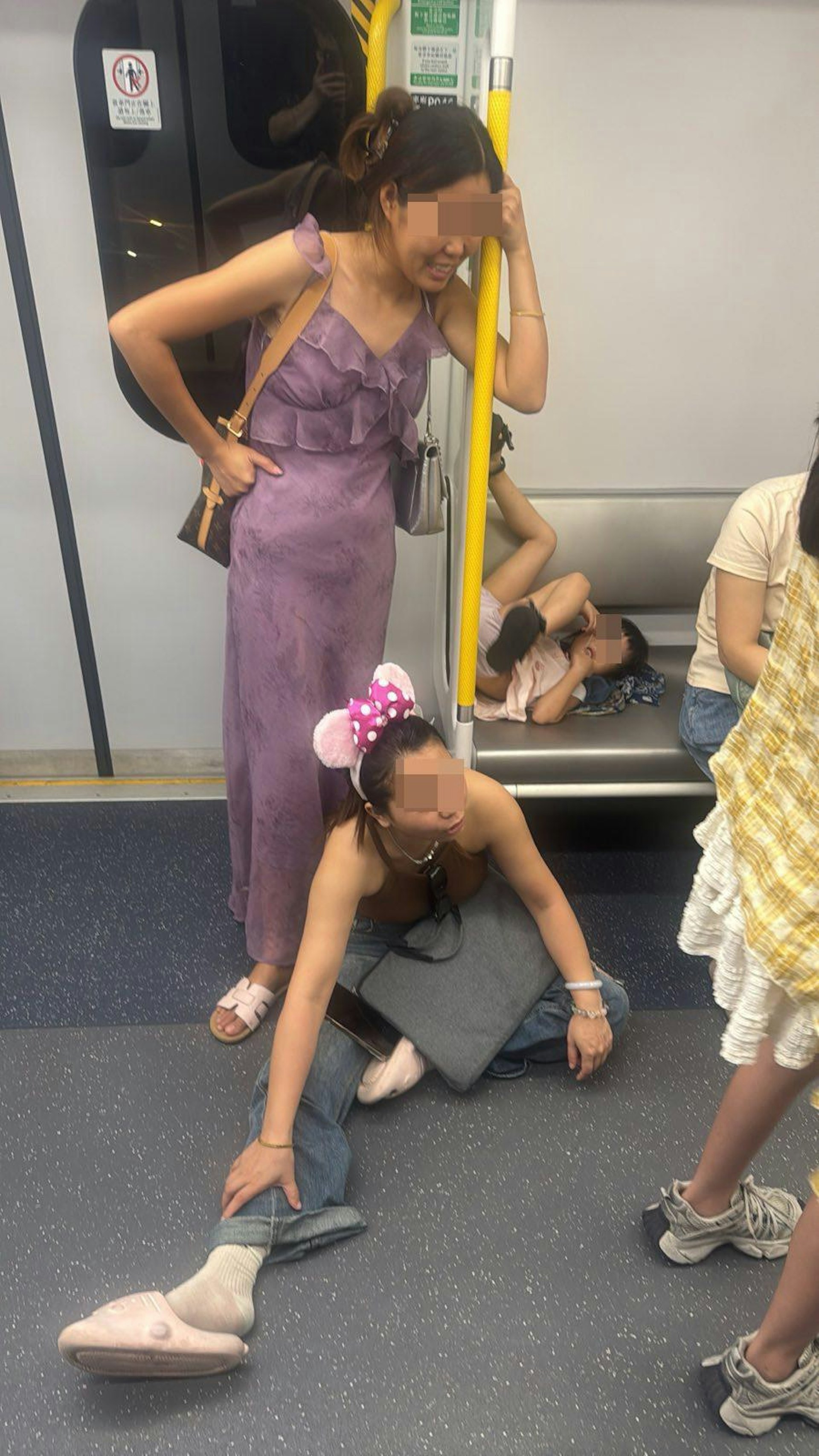 第1張相見到,頭戴迪士尼米奇老鼠樣式頭箍女子坐在座位前地上,並把右腳伸長霸佔了車廂通道,座位上有1名女童倒轉身體把穿着鞋的腳踩在扶手玻璃上。(Facebook群組「上水人大聯盟」)