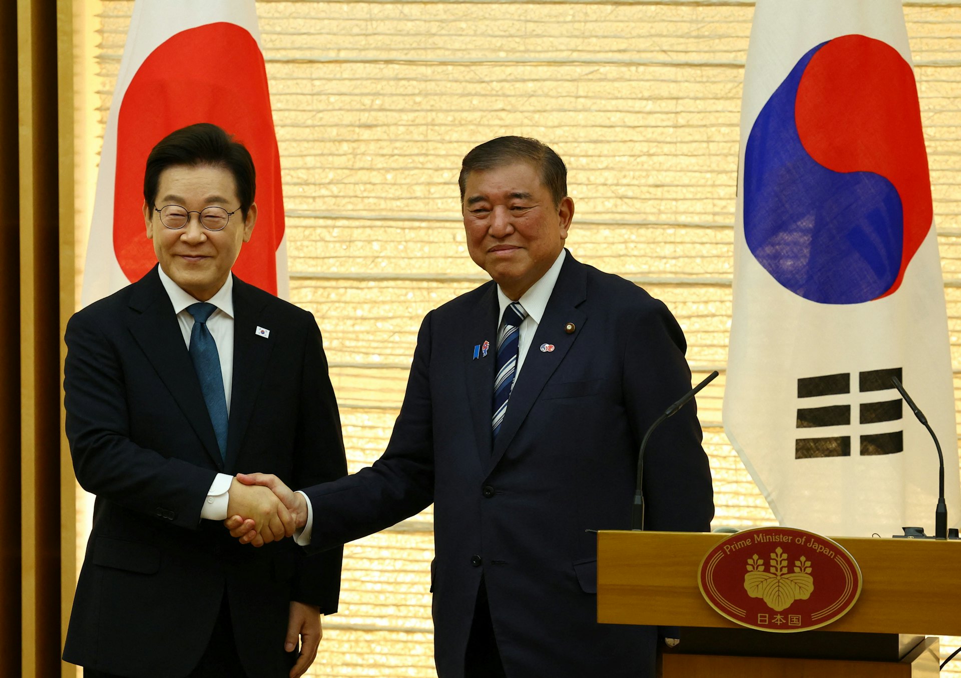 韓國總統李在明(左)2025年8月23日會晤日本首相石破茂(右),兩人在聯合記者會上握手(REUTERS/Pool)