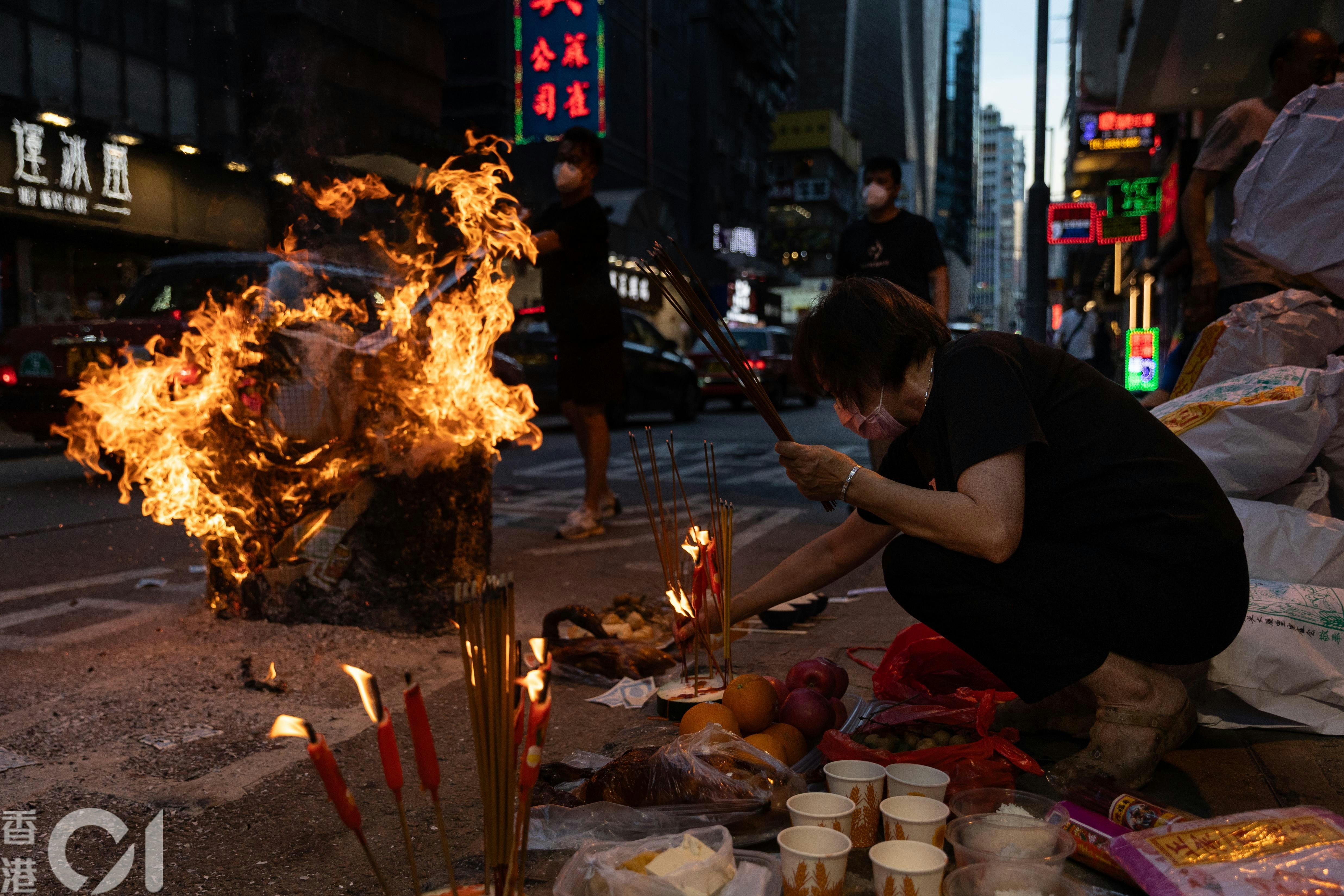 农历七月路边火光摇曳，市民焚衣祭祀，布施孤魂，祈求平安，既是古老传统，亦是街头巷尾的社区风景。（廖雁雄摄）
