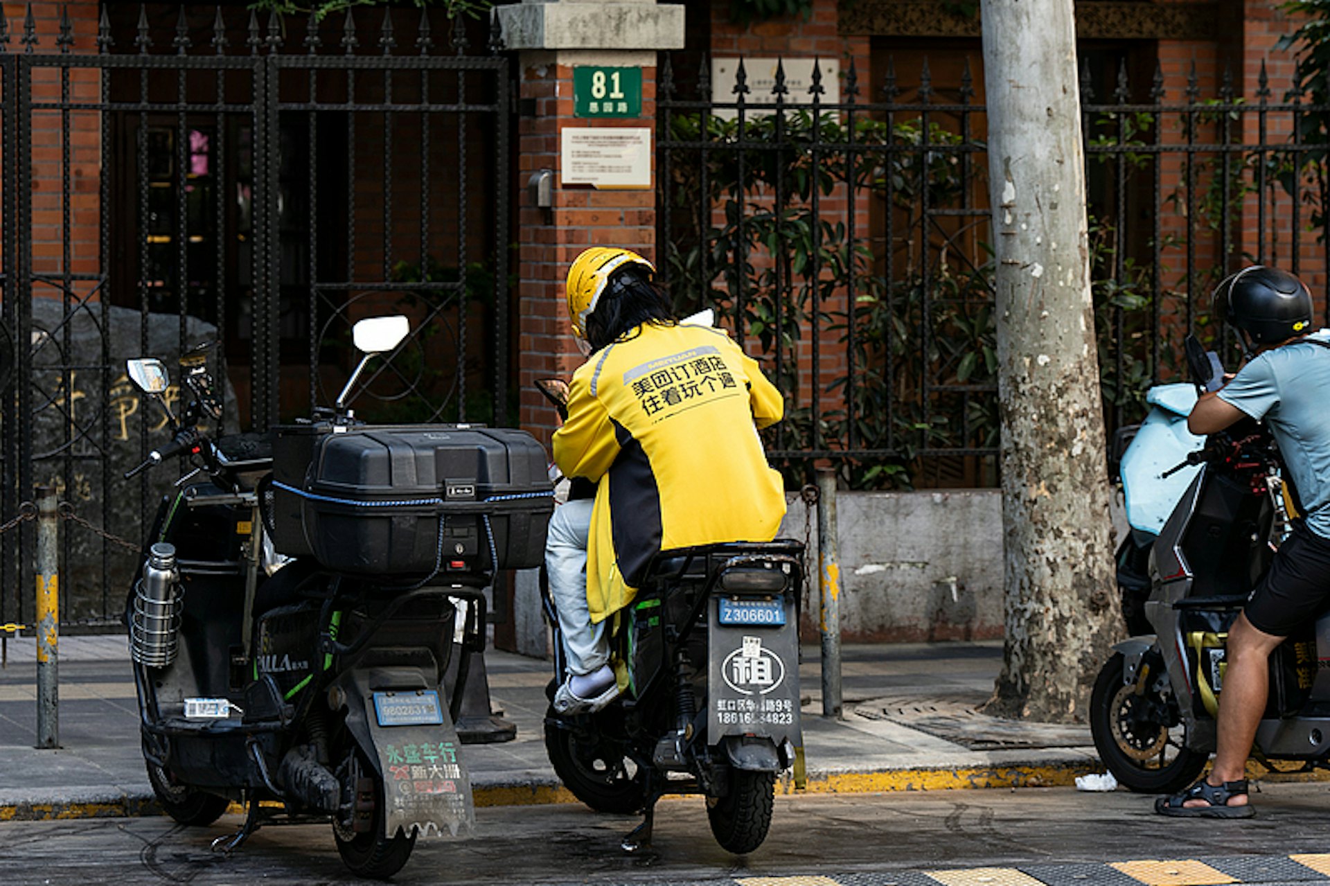 2025年8月25日,中國上海,一名美團外賣配送員坐在摩托車上。(CFP) 2025年8月25日,中國上海,一名美團外賣配送員坐在摩托車上。(CFP)