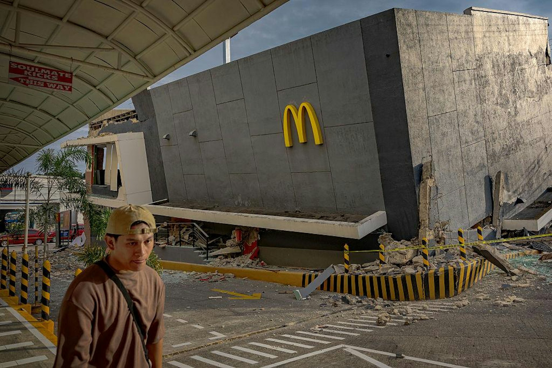 2025年10月1日,菲律賓宿霧省,圖為當地發生6.9級地震後,有民眾途徑一處倒塌建築。(Getty) 2025年10月1日,菲律賓宿霧省,圖為當地發生6.9級地震後,有民眾途徑一處倒塌建築。(Getty)