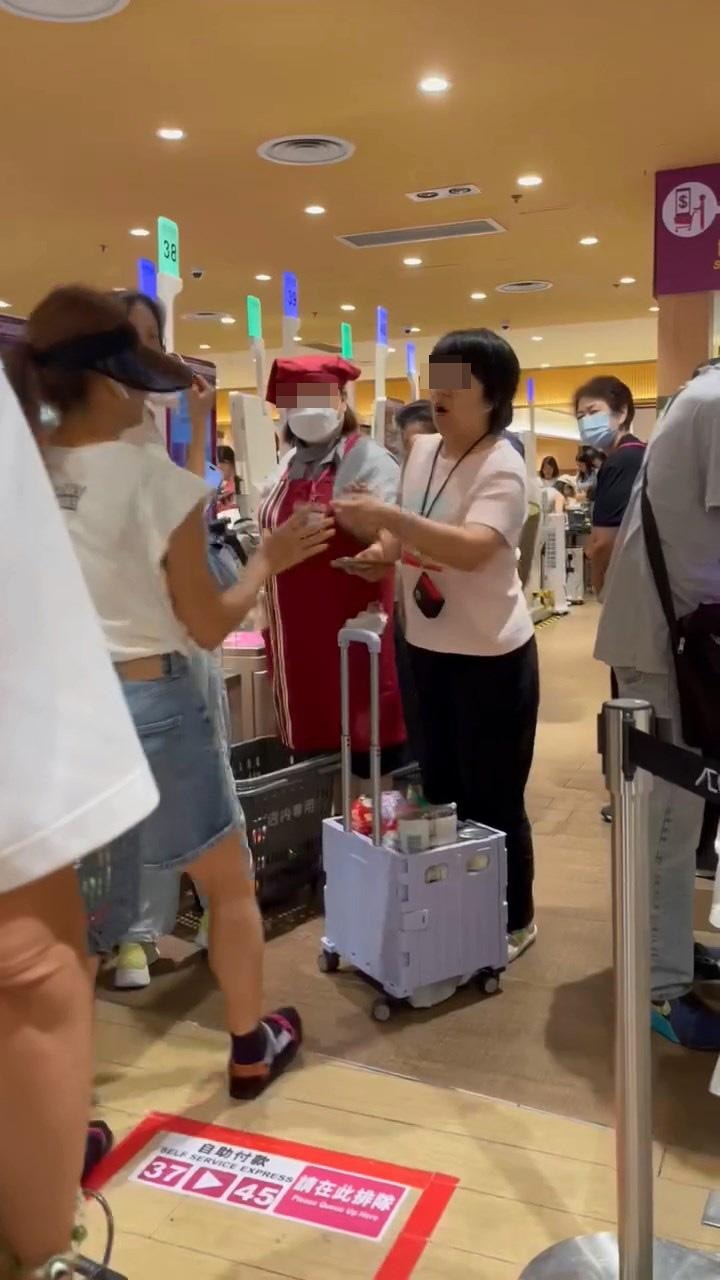 穿粉色上衣的鄉音大媽目露兇光,把港女的「買餸車」一手抬高,再翻倒掉在地上,令內裏貨物散落一地。(網絡影片截圖)