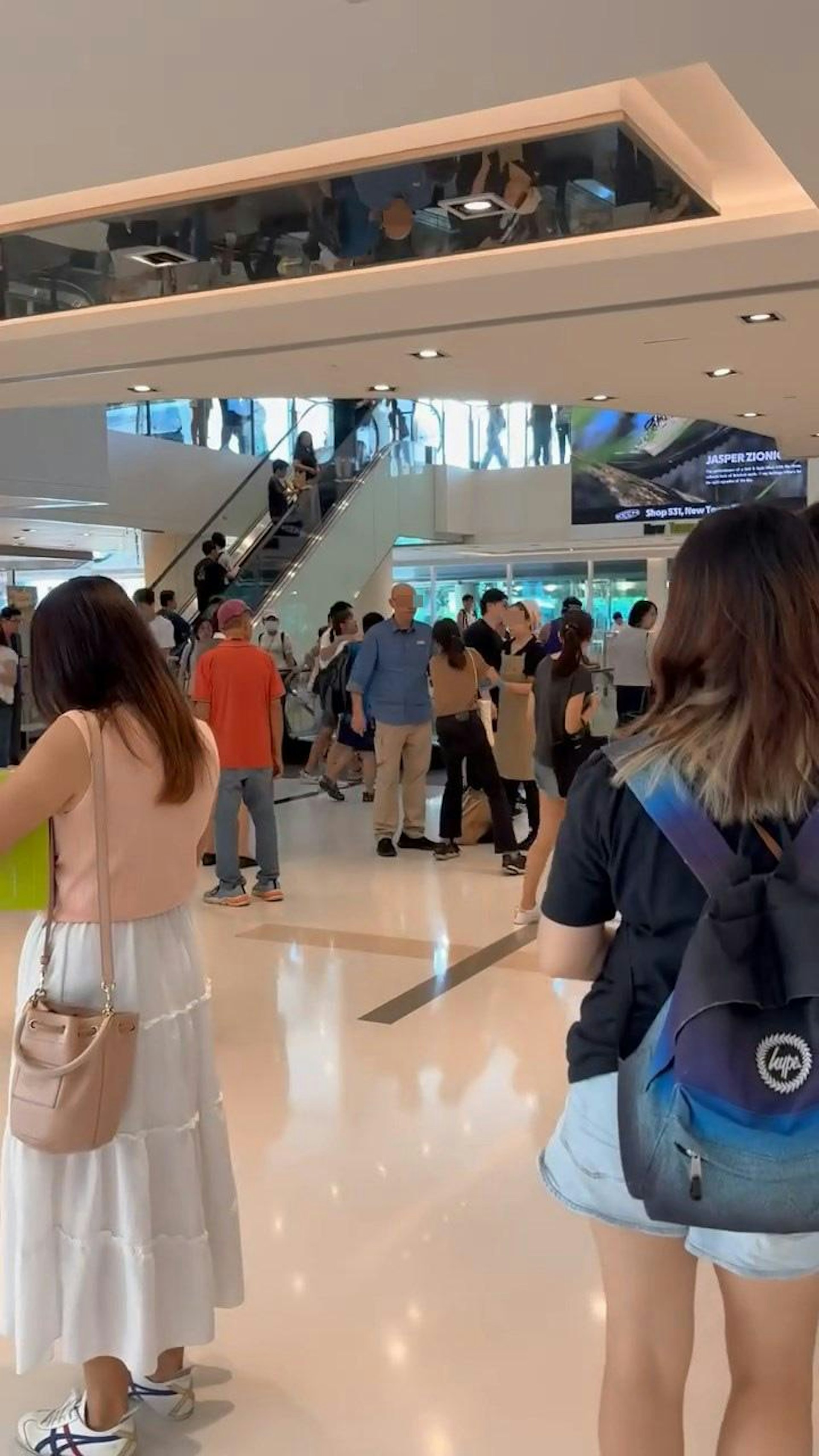 沙田新城市廣場當時人來人往,平地中間位置有1名穿啡色上衣女子,被1名疑似男店長與1名女店員分別捉實右手和左手。(Threads@l.man_crystal)