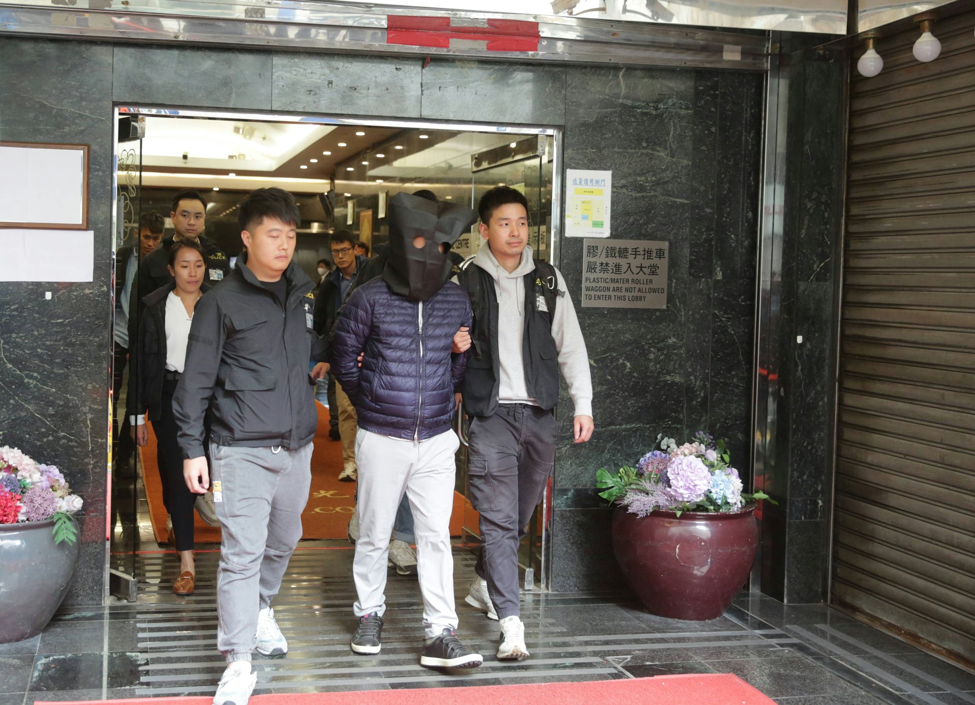 早上9時左右,警方以黑布蒙頭帶走一名男子。(黃偉民攝)