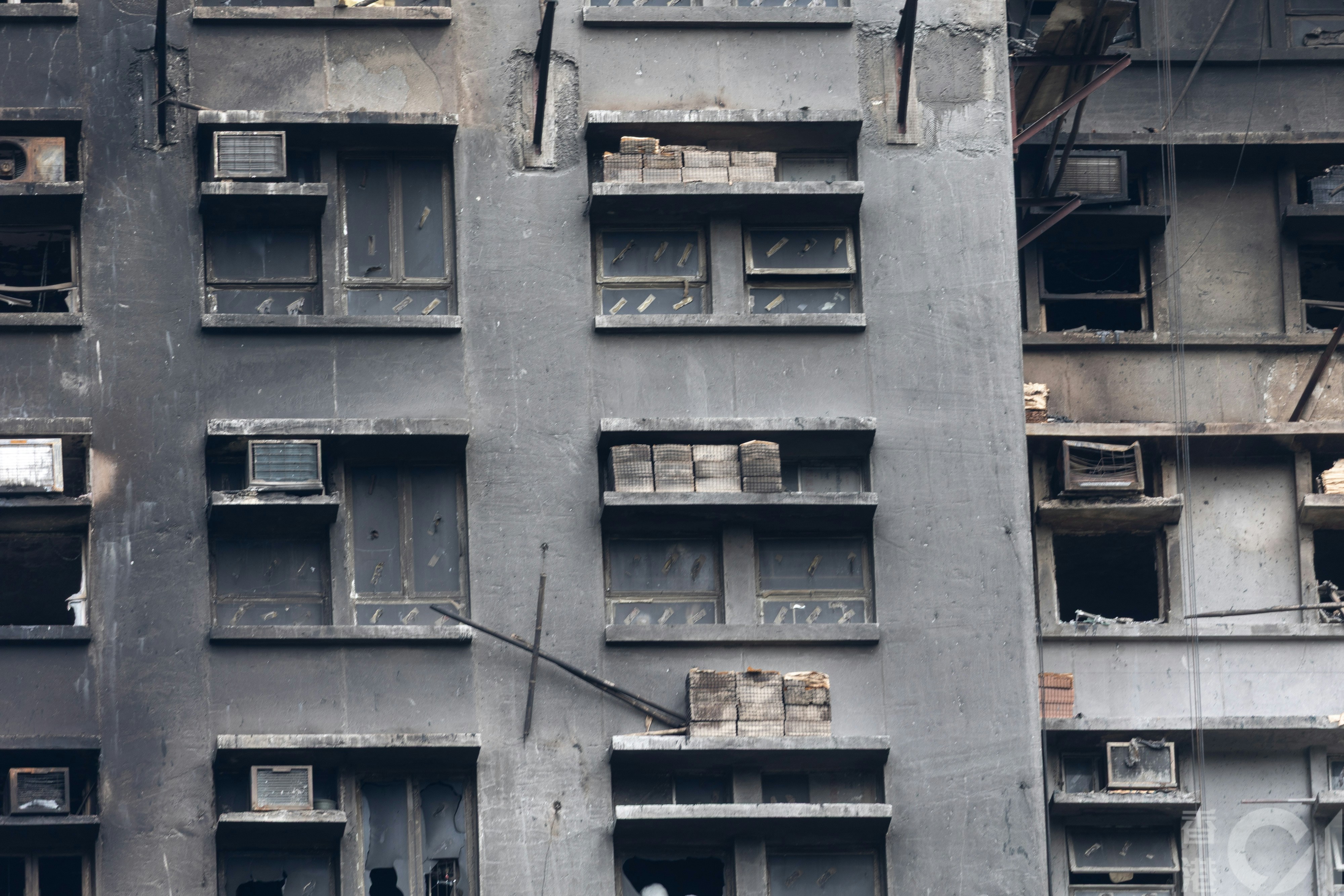 12月1日在大埔宏福苑可見，一些窗簷擺放了鋪設外牆的紙皮石，部份無爆破玻璃窗留有一條條膠紙，料是用來黏貼發泡膠板。（夏家朗攝）