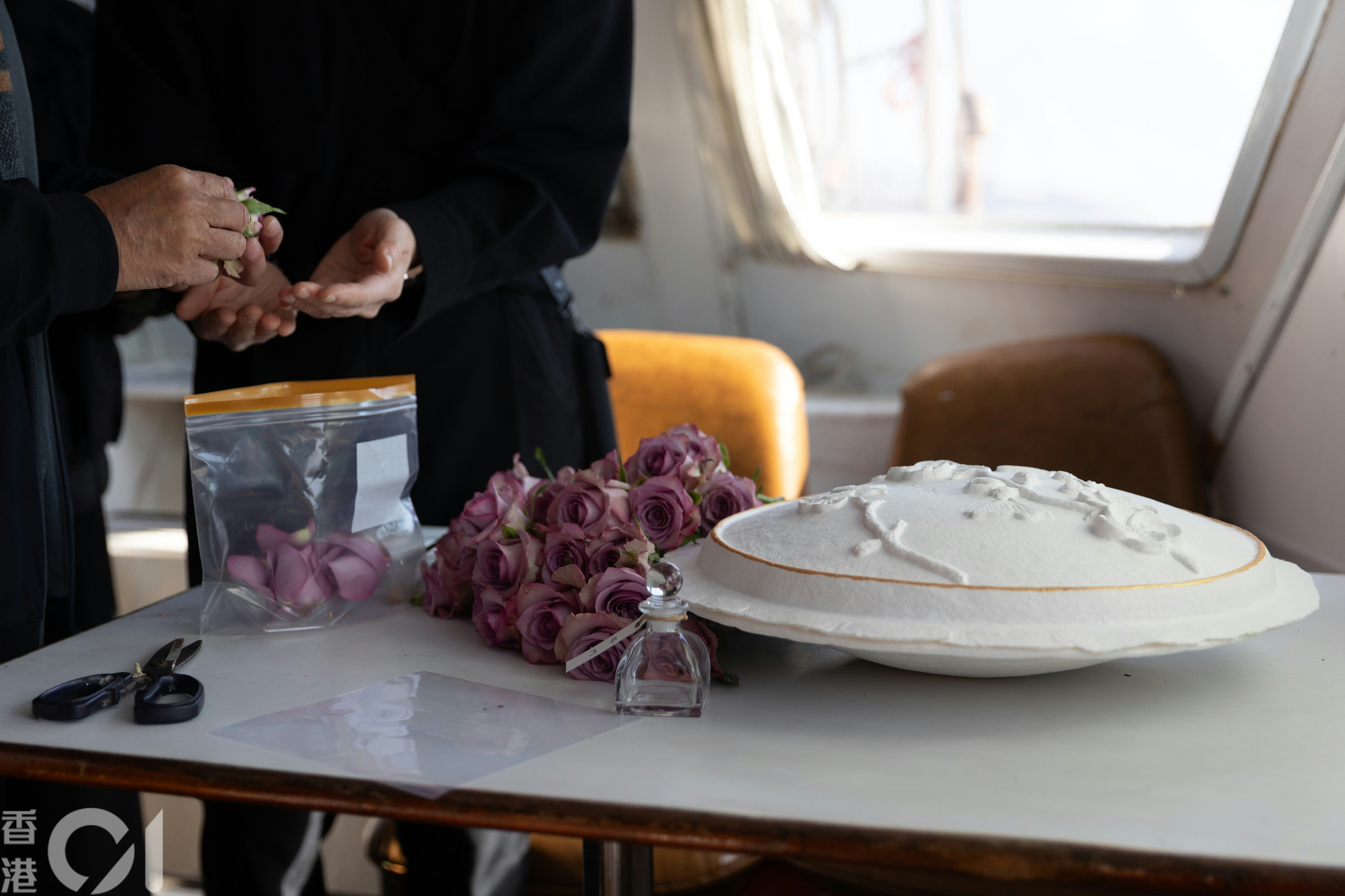 葉先生與家人在船上將紫色玫瑰的花瓣摘下，為撒灰儀式作準備。（廖雁雄攝）