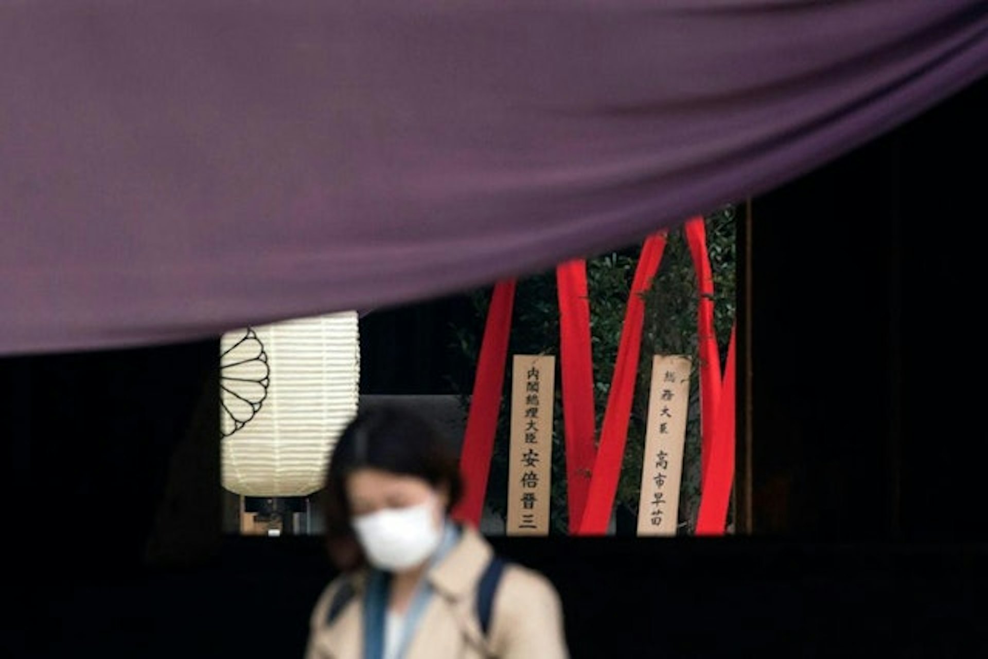 2020年4月21日,日本東京,圖為一名戴口罩的女子途徑由時任日本首相安倍晉三與時為內閣成員高市早苗,共同為靖國神社供奉的祭品。(Getty) 2020年4月21日,日本東京,圖為一名戴口罩的女子途徑由時任日本首相安倍晉三與時為內閣成員高市早苗,共同為靖國神社供奉的祭品。(Getty)