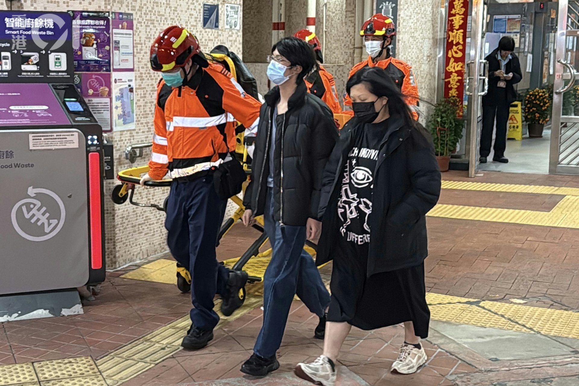 男鄰居(中)吸入濃煙不適,由母親及救護員陪同,行上救護車接受治理。(李家傑攝) 男鄰居(中)吸入濃煙不適,由母親及救護員陪同,行上救護車接受治理。(李家傑攝)