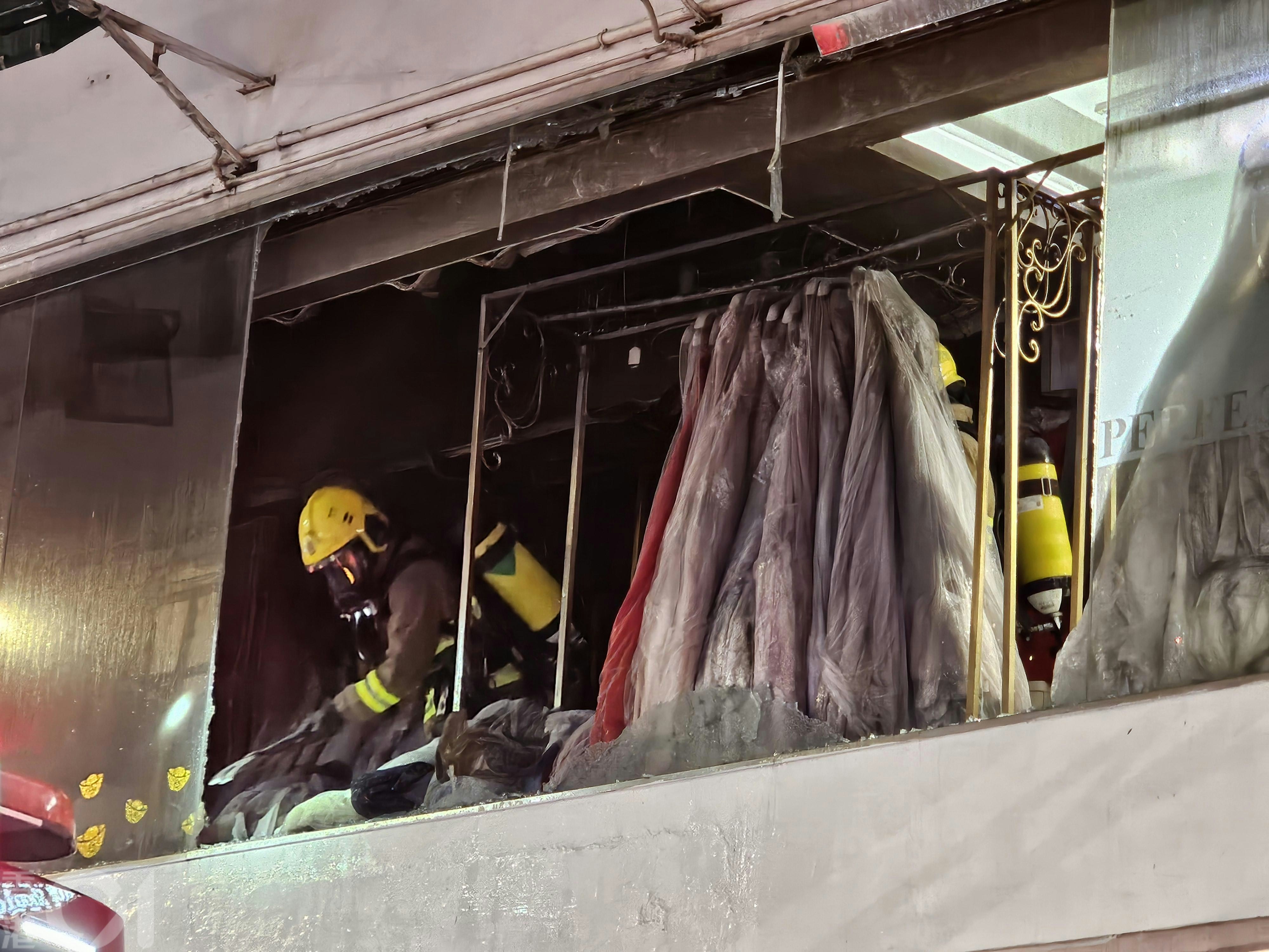 現場可見，涉事婚紗店櫥窗粉碎，碎片散落行人路上；掛在窗邊衣架上的多件婚紗及禮服被熏黑。（梁偉權攝）