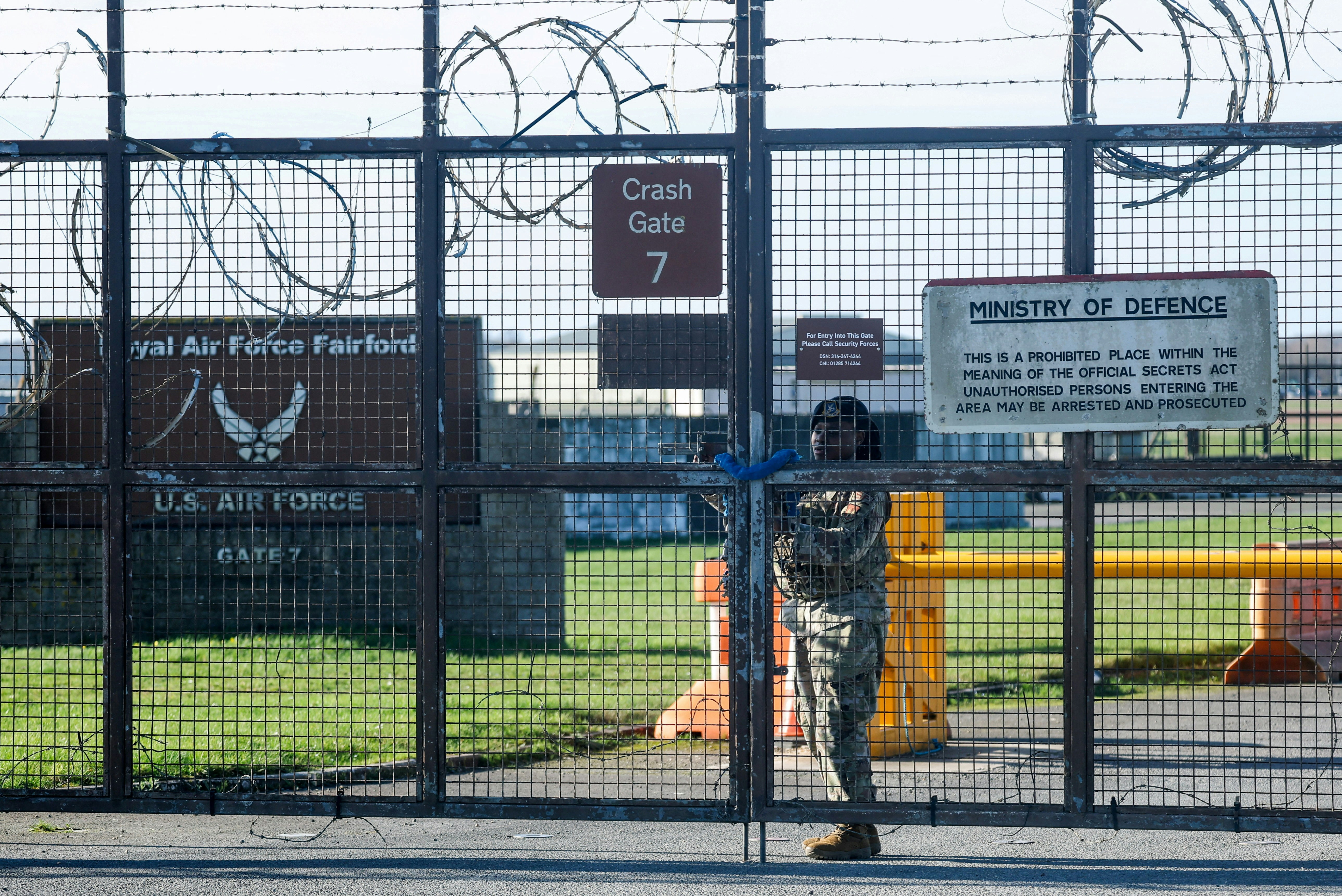 2026年3月2日，在英國費爾福德，一名美軍士兵在皇家空軍費爾福德基地外圍圍欄上加固大門。（Reuters）