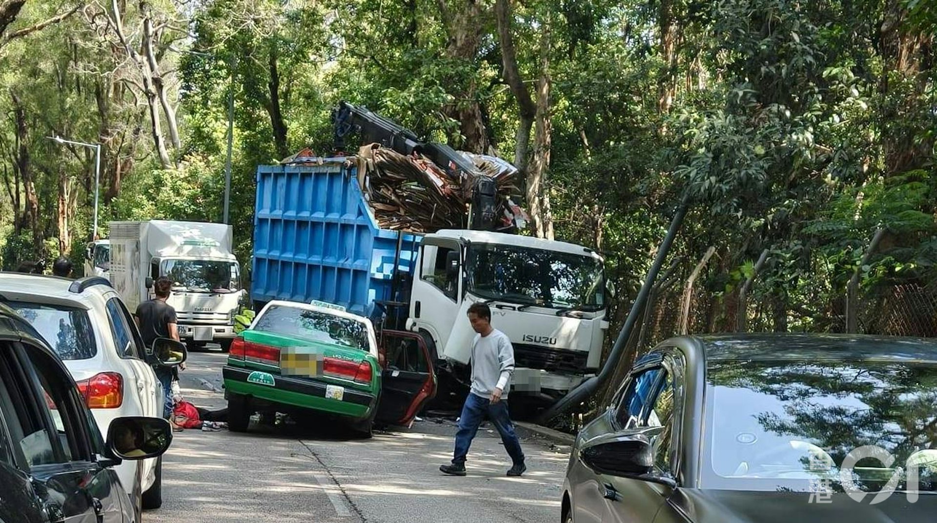 身穿紅衣的老婦被救出車廂,倒臥在的士旁。(讀者陳先生提供)