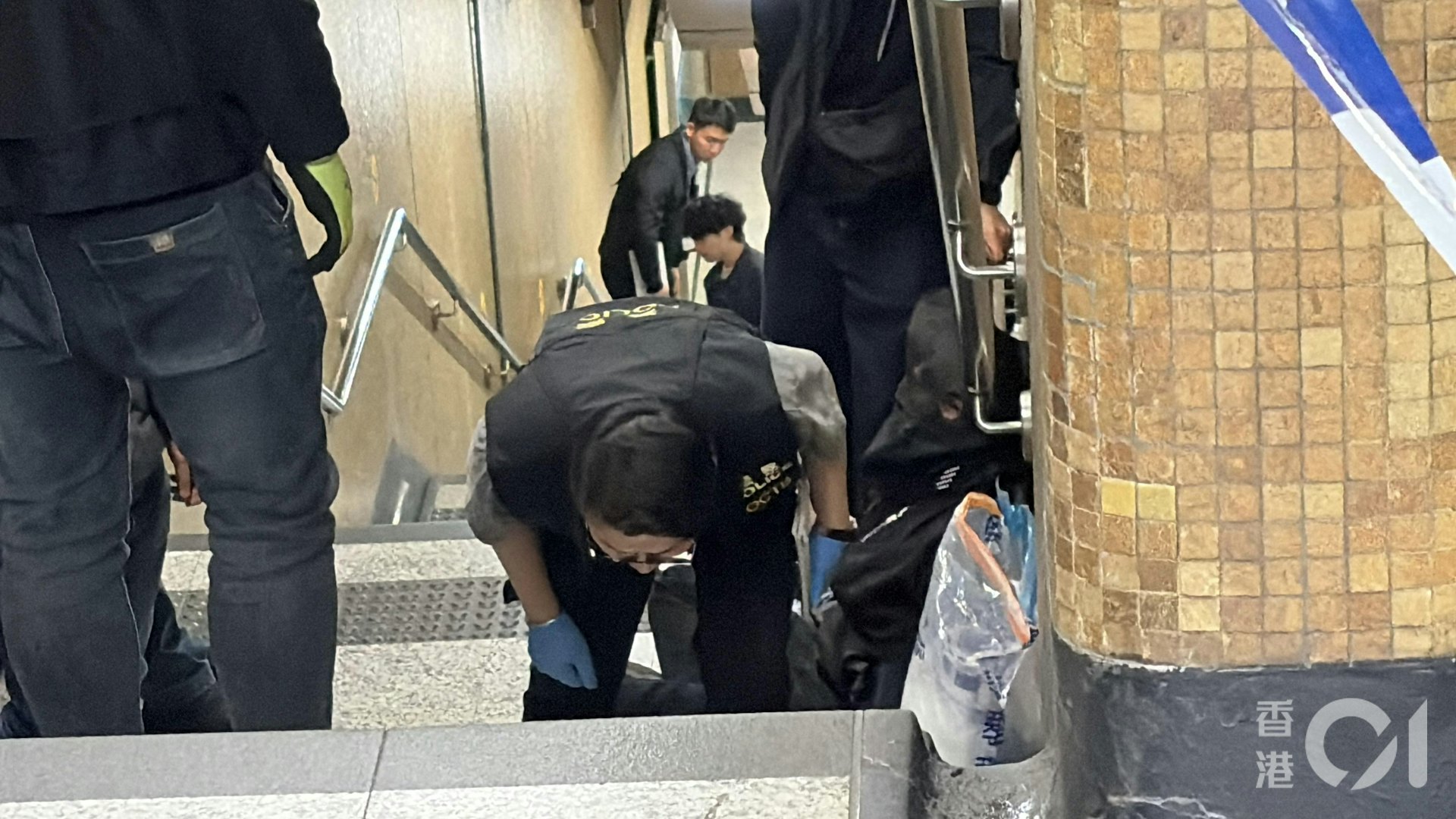 被捕人蒙黑色頭套一左一右坐在上環地鐵站B出口樓梯,被多名警員看守。(黃煦緻攝) 被捕人蒙黑色頭套一左一右坐在上環地鐵站B出口樓梯,被多名警員看守。(黃煦緻攝)