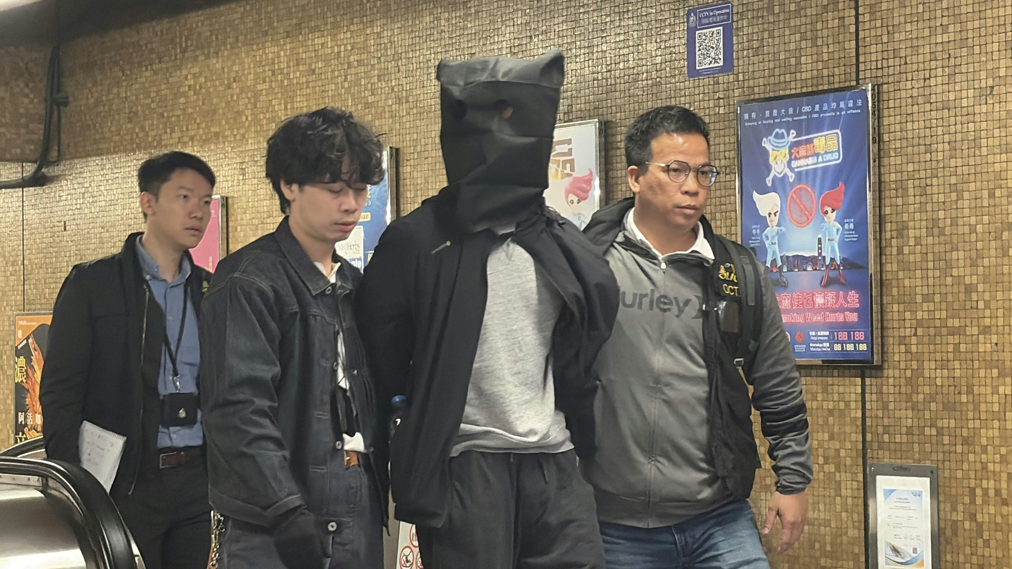 O記探員將一名穿黑色外套及灰色衫被捕人帶出地鐵站。（黃煦緻攝）