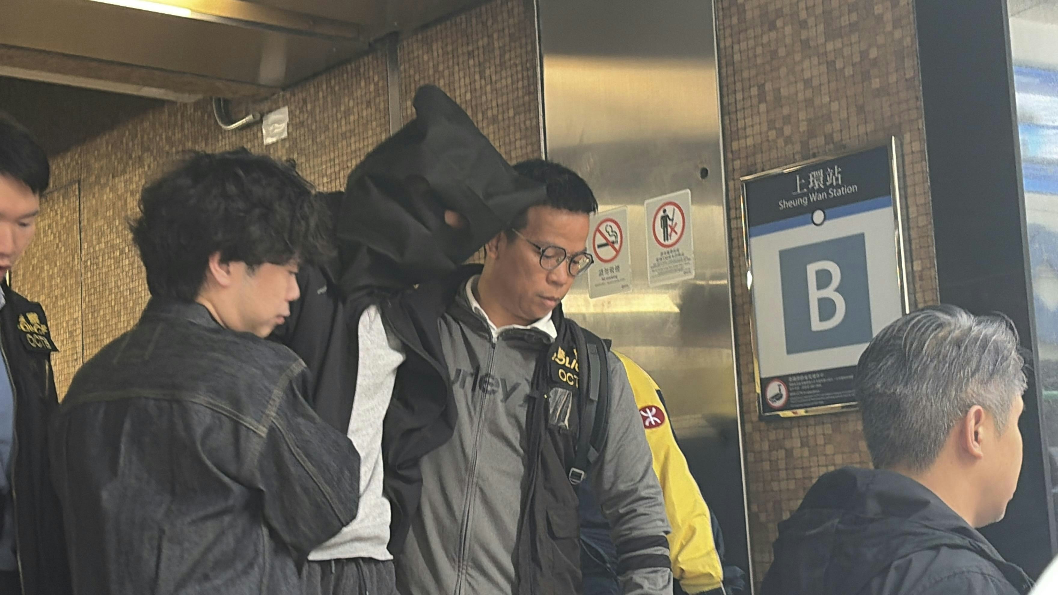 O記探員將一名穿黑色外套及灰色衫被捕人帶出地鐵站。（黃煦緻攝）