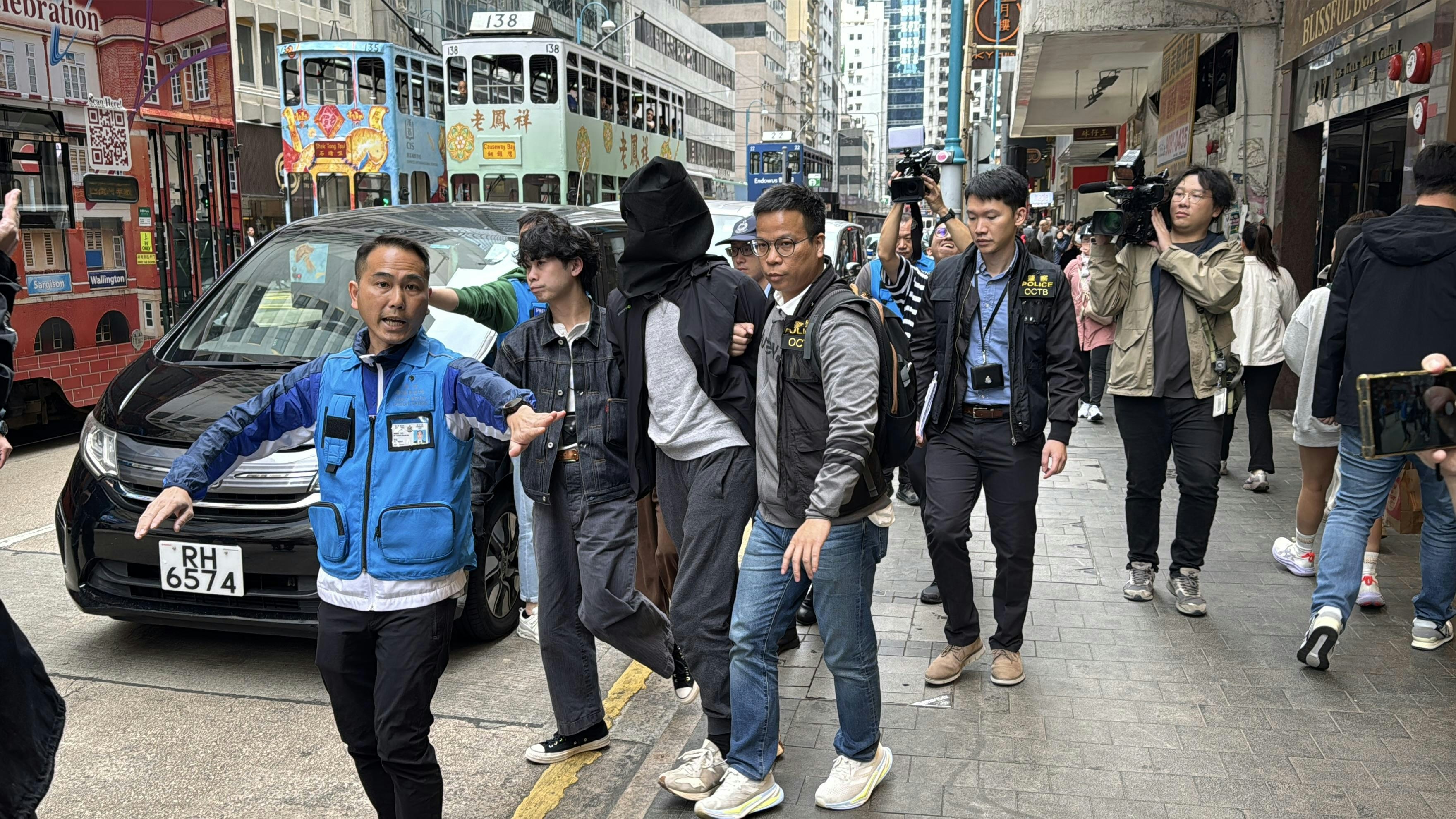 O記探員將一名穿黑色外套及灰色衫被捕人帶出地鐵站。（翁鈺輝攝）