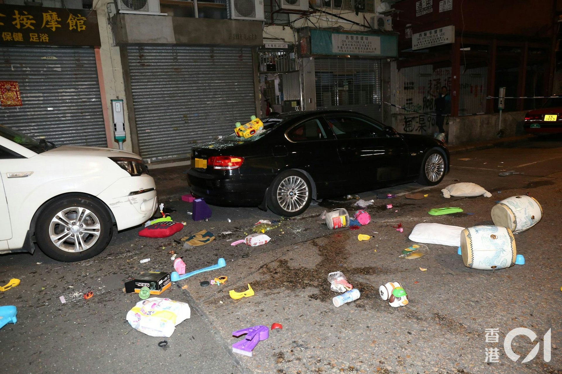 大批雜物從單位窗邊墮下,擊穿樓下私家車車尾車窗,仍然懸掛一個黃色玩具車,馬路散落大量玩具和家居用品,例如枕頭和尿片。(陳永武攝)