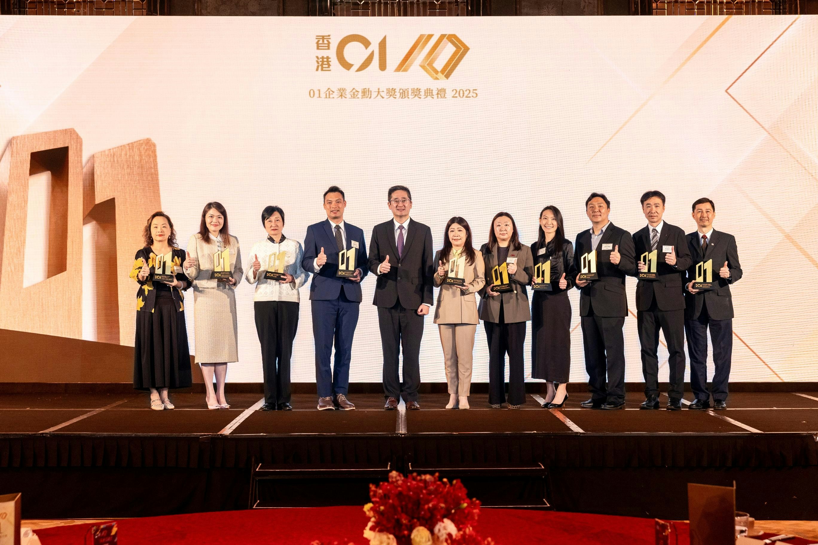 2026年3月20日，《香港01》舉辦第六屆「01企業金勳大獎」頒獎禮，商務及經濟發展局副局長陳百里（左五）頒獎予得獎公司代表。（《香港01》圖片）
