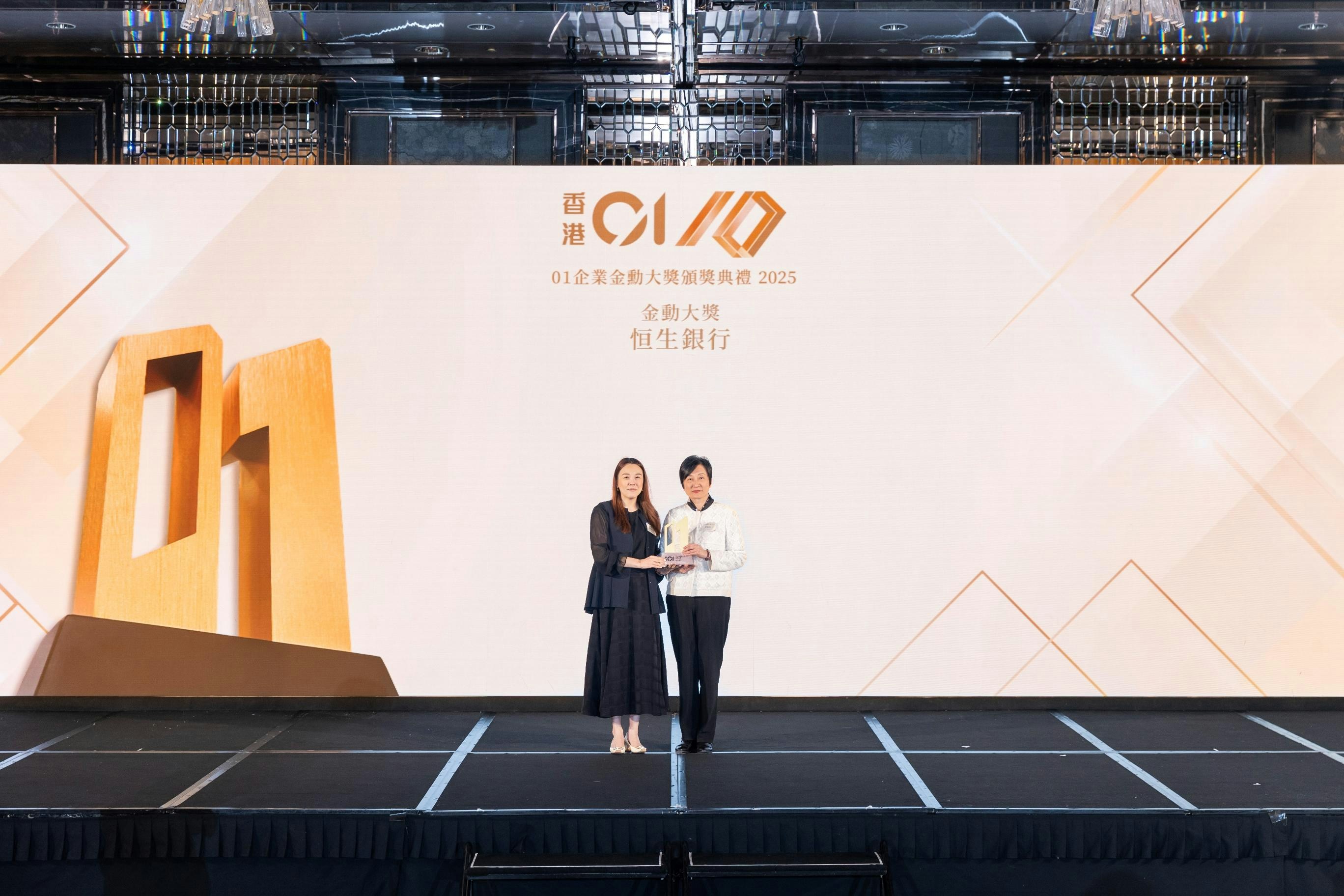 《香港01》行政總裁蘇曉婷女士(左)頒發「金勳大獎」多恒生銀行財富管理及個人銀行業務主管李樺倫女士(右)。(《香港01》圖片)