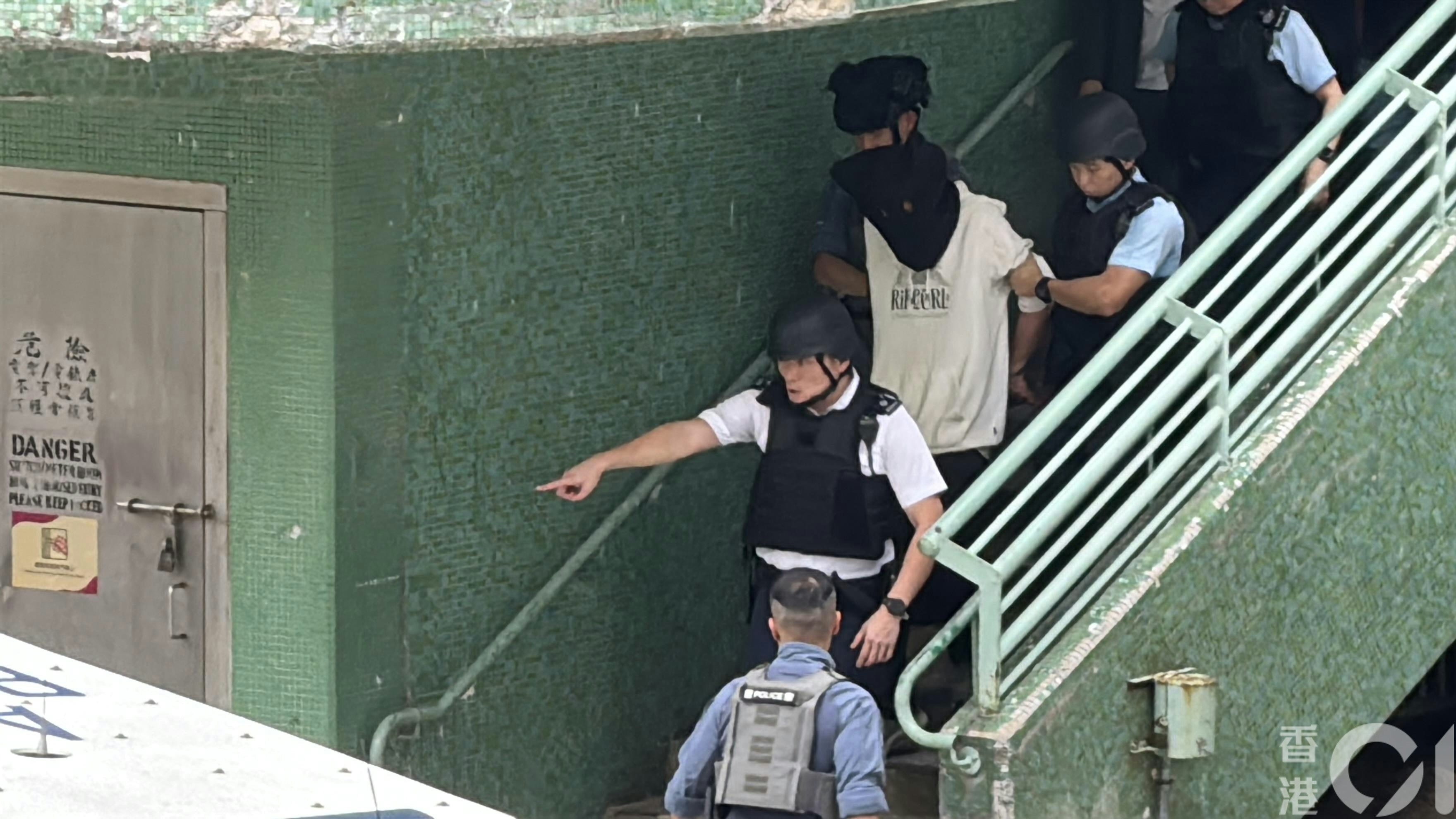 疑犯黑布蒙頭被帶走。（翁鈺輝攝）