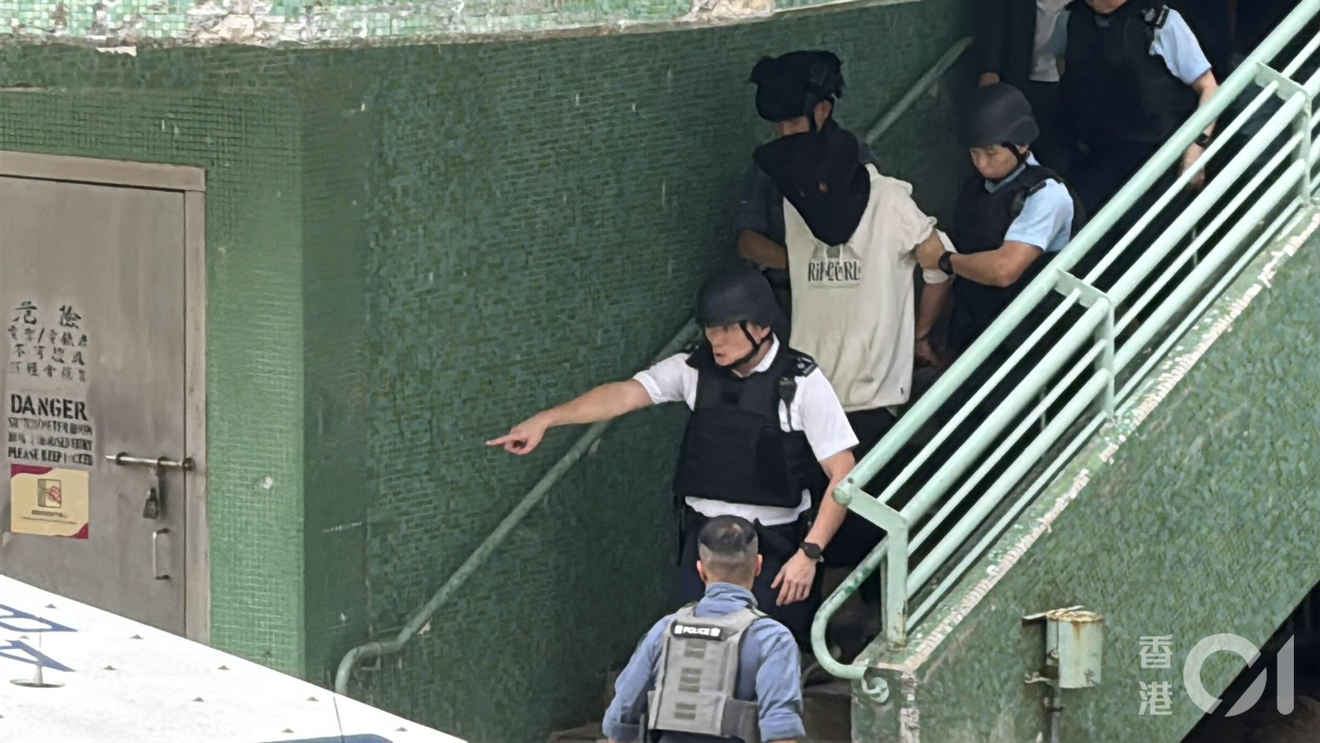 疑犯黑布蒙頭被帶走。(翁鈺輝攝)