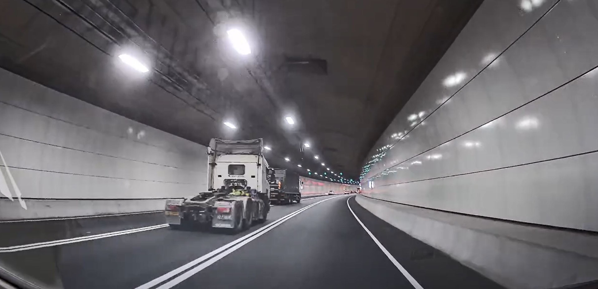 一輛密斗貨車沿中線風馳電掣駛至,隨後無視雙白線切入左線,另一輛未見掛上貨櫃或拖架的拖頭從中線後方狂飆。(Facebook群組「車cam L(香港群組)」/Fion Kwok影片截圖)