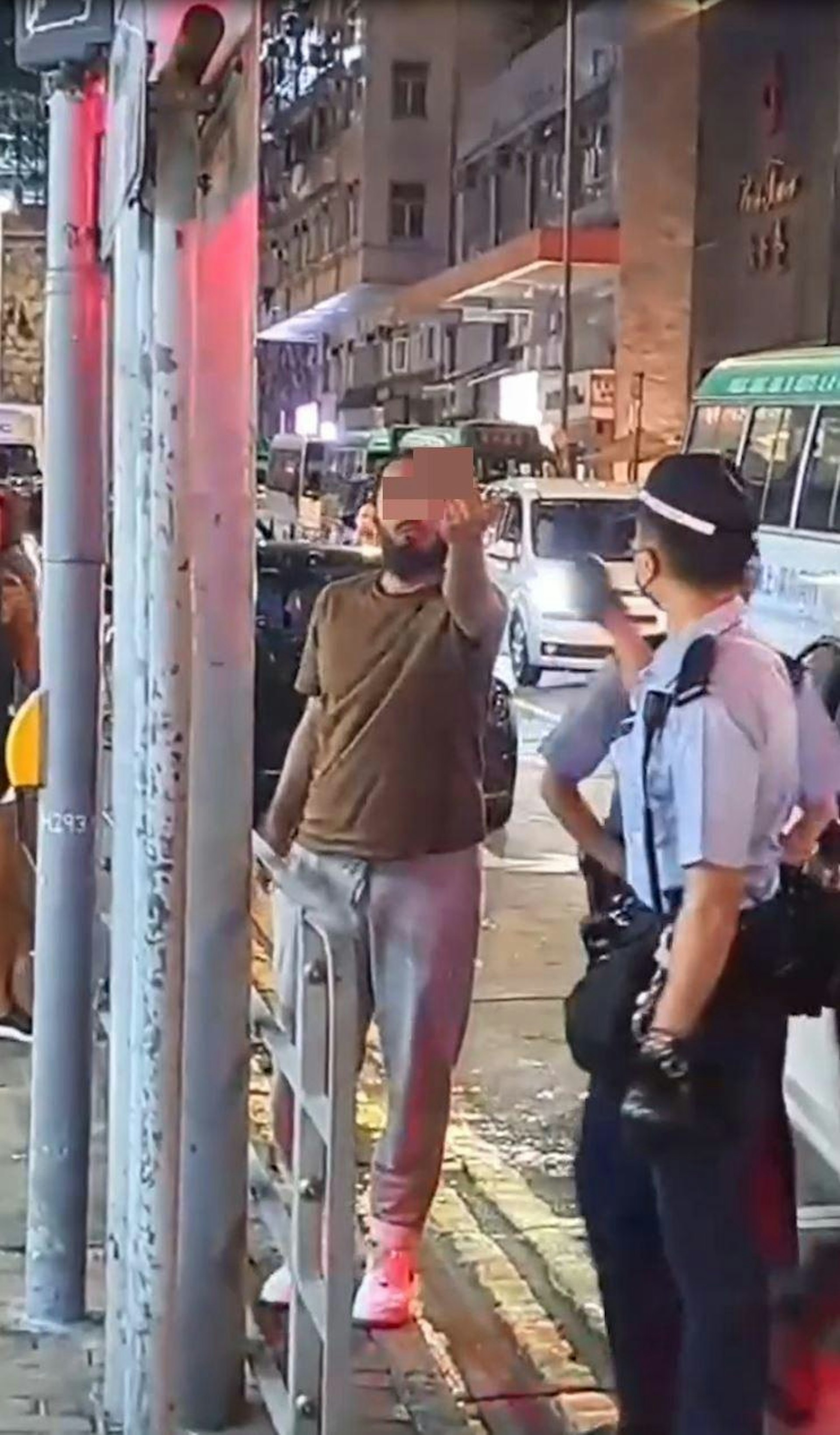 該名非華裔男子見到途人用手機拍片,立即舉起中指,再次爆粗「X你老X」。(網上影片截圖) 該名非華裔男子見到途人用手機拍片,立即舉起中指,再次爆粗「X你老X」。(網上影片截圖)