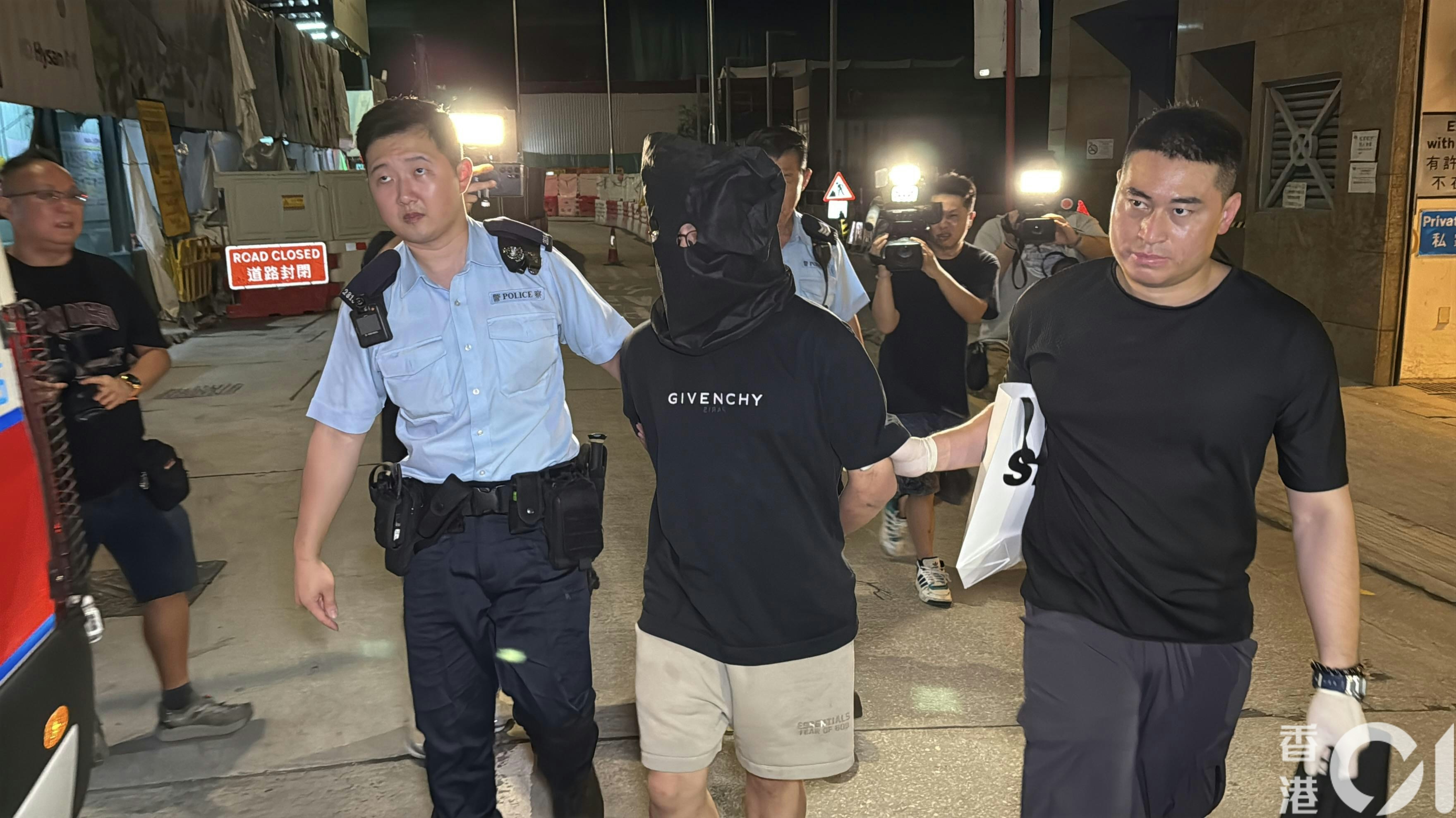 被捕司機黑布蒙頭，被帶上警車。（李家傑攝）