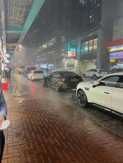 沒有穿上雨衣的男警員，冒着風雨淋身走出簷篷抄牌。（網絡圖片）
