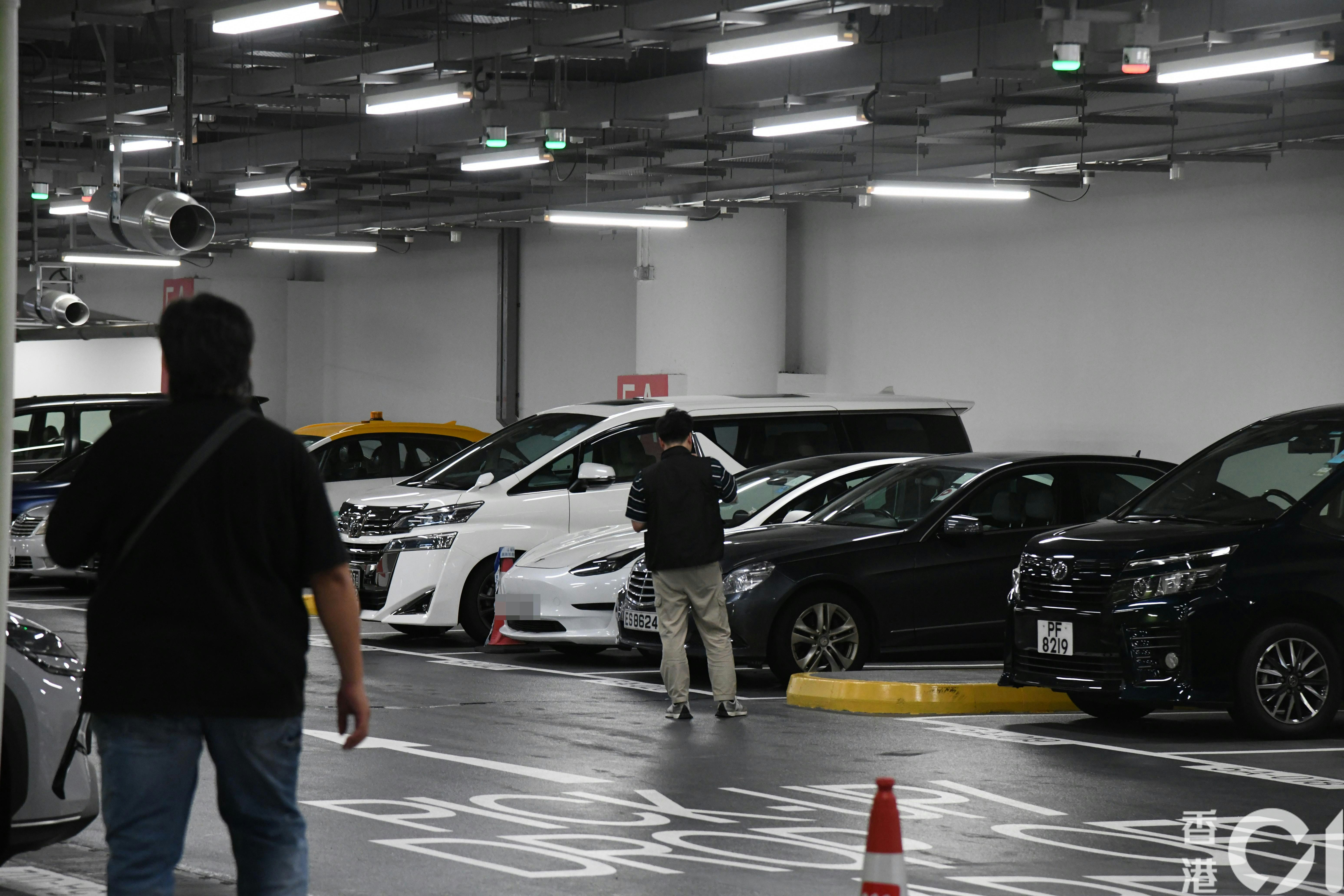 警員在白色Tesla私家車停泊車位一帶調查。