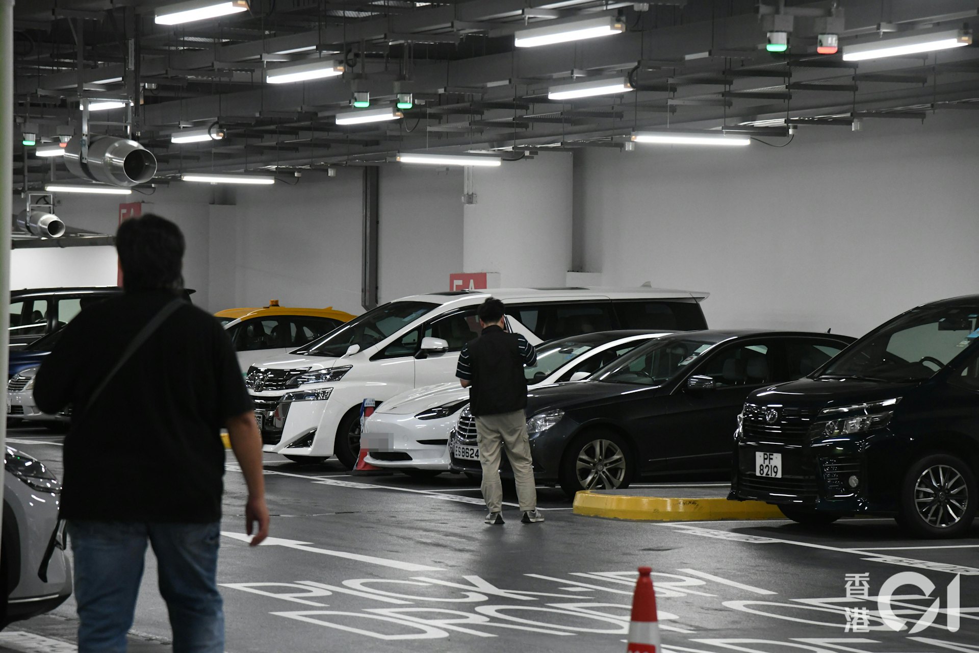 警員在白色Tesla私家車停泊車位一帶調查。 警員在白色Tesla私家車停泊車位一帶調查。
