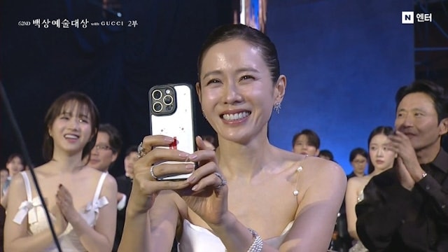 孙艺珍在活动现场微笑举起手机的画面