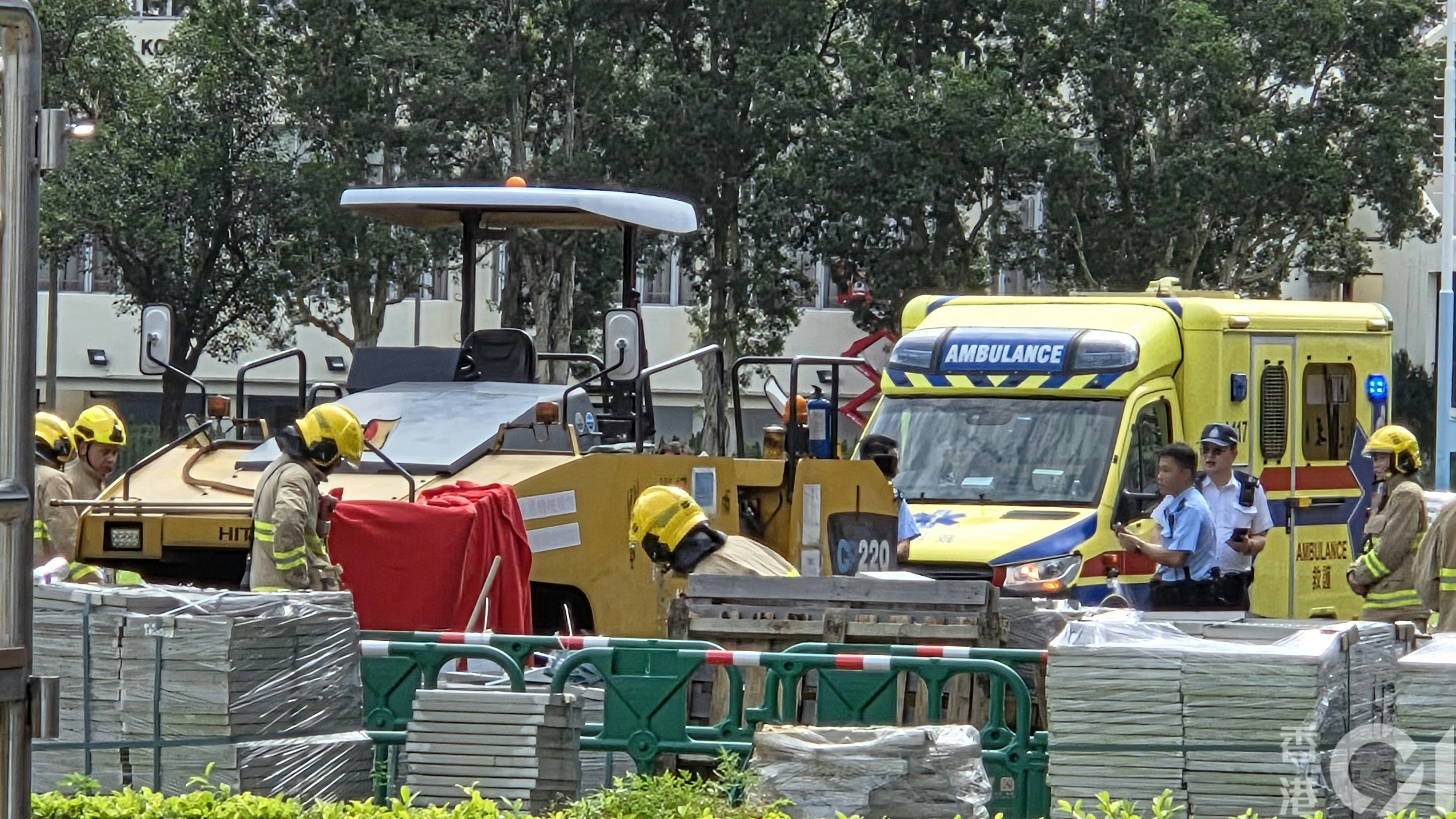 男工被道路工程車輾過，消防員到場用紅布遮蓋工程車左邊車頭。（黃偉民攝）