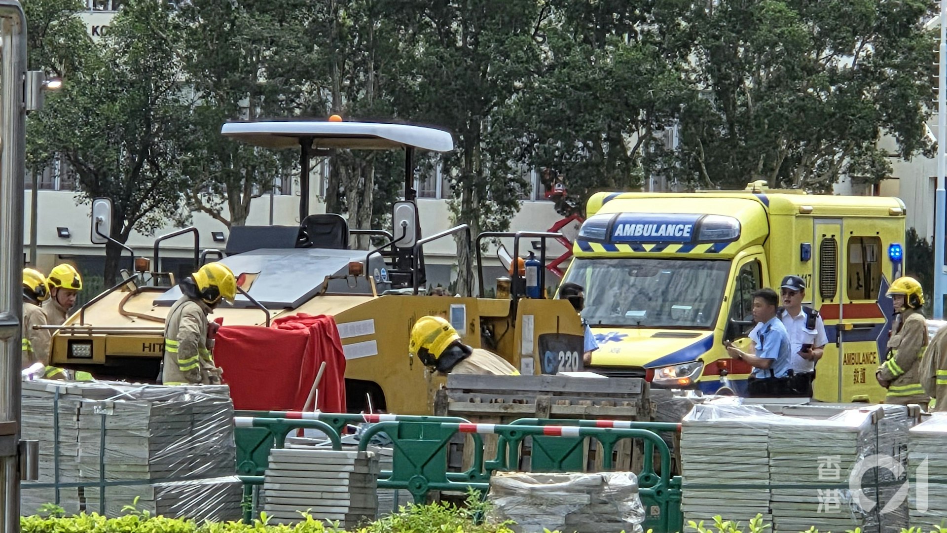 男工被道路工程車輾過,消防員到場用紅布遮蓋工程車左邊車頭。(黃偉民攝) 男工被道路工程車輾過,消防員到場用紅布遮蓋工程車左邊車頭。(黃偉民攝)