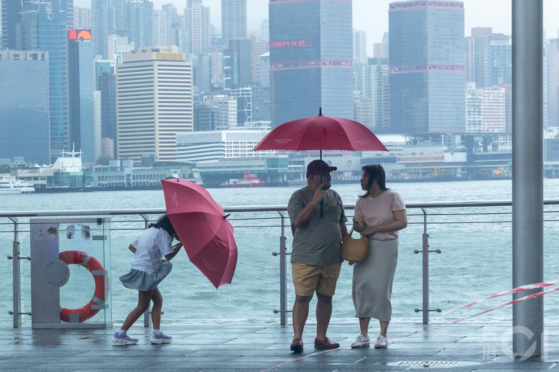 尖沙咀近中午时分8号风球仍生效期间,有市民及游客特别到来感受台风红霞的余威,当中也有小朋友「顶住」强风。