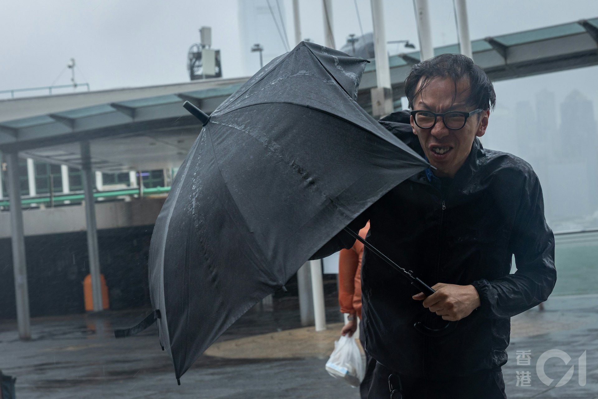尖沙咀近中午时分8号风球仍生效期间,有市民及游客特别到来感受台风红霞的余威,雨伞被吹烂。