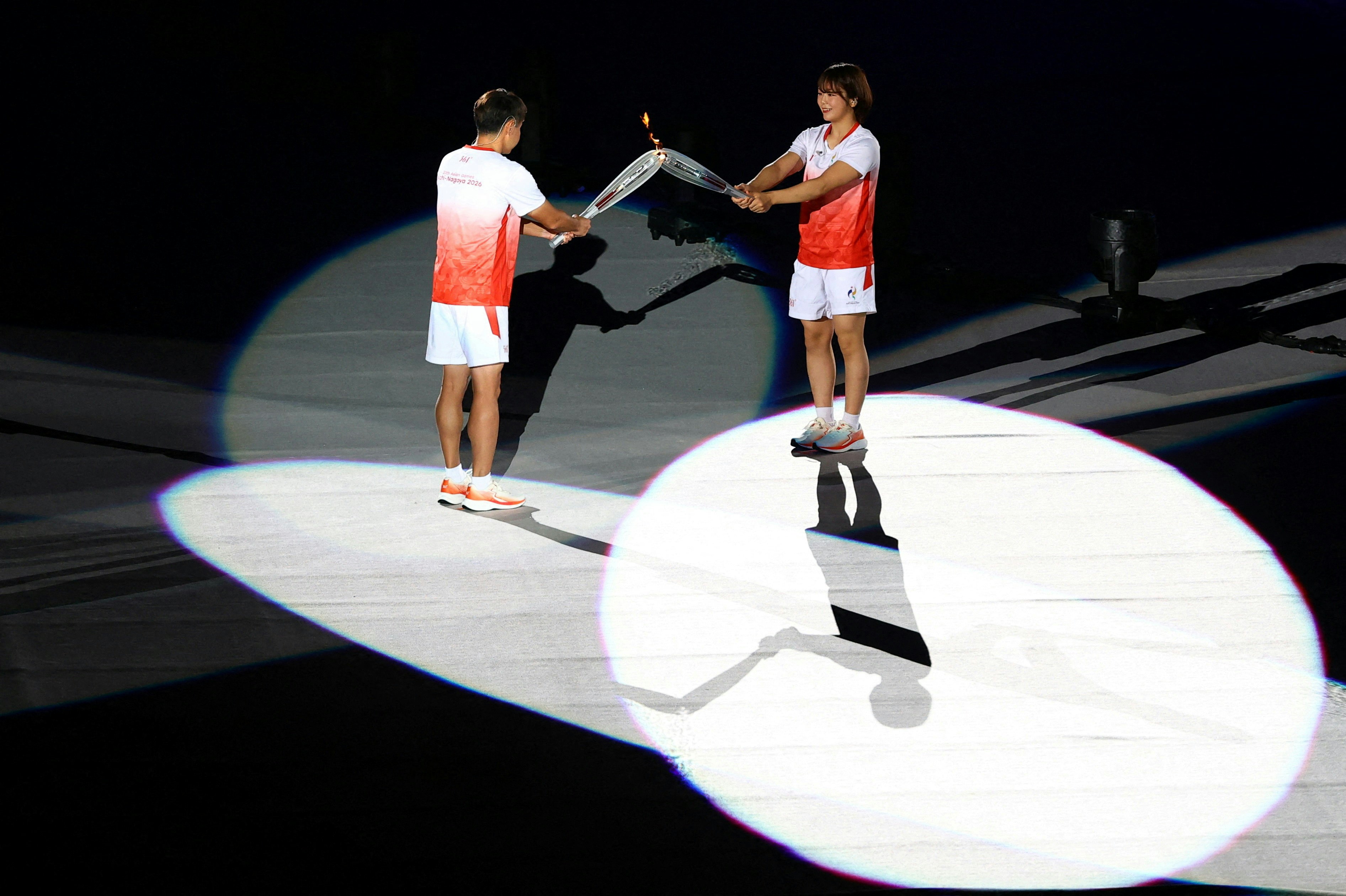 2026年9月19日，名古屋亚运会开幕礼，运动员正在传递火炬。（Reuters）