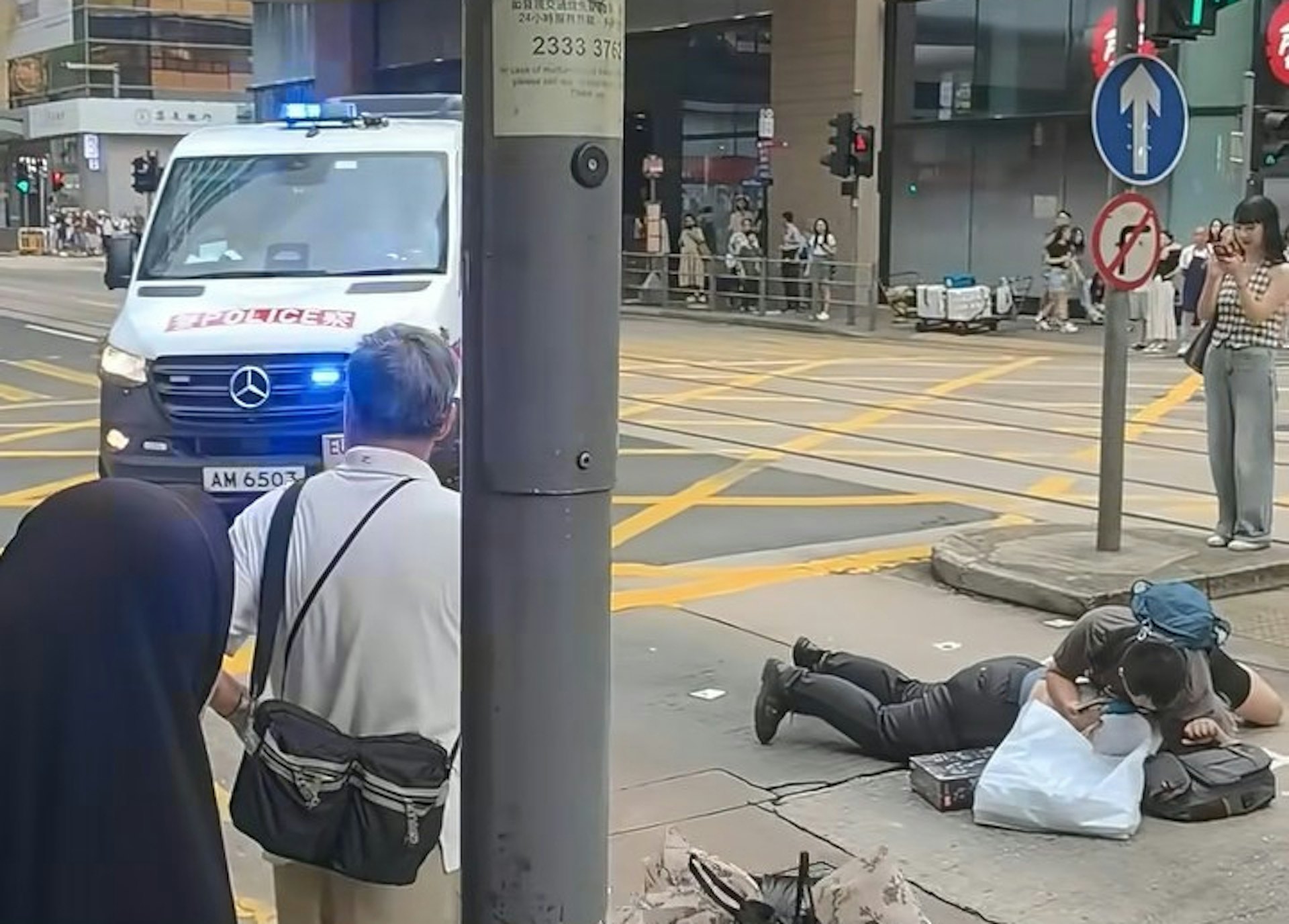 兩名男子疑在中環德輔道中與租庇利街交界,因身體碰撞爆發衝突,其中一名穿短褲、揹藍色背囊的男子,將另一名穿長褲的男子壓在地上。警員接報趕到現場。(小紅書/小红薯6AB38E3F)