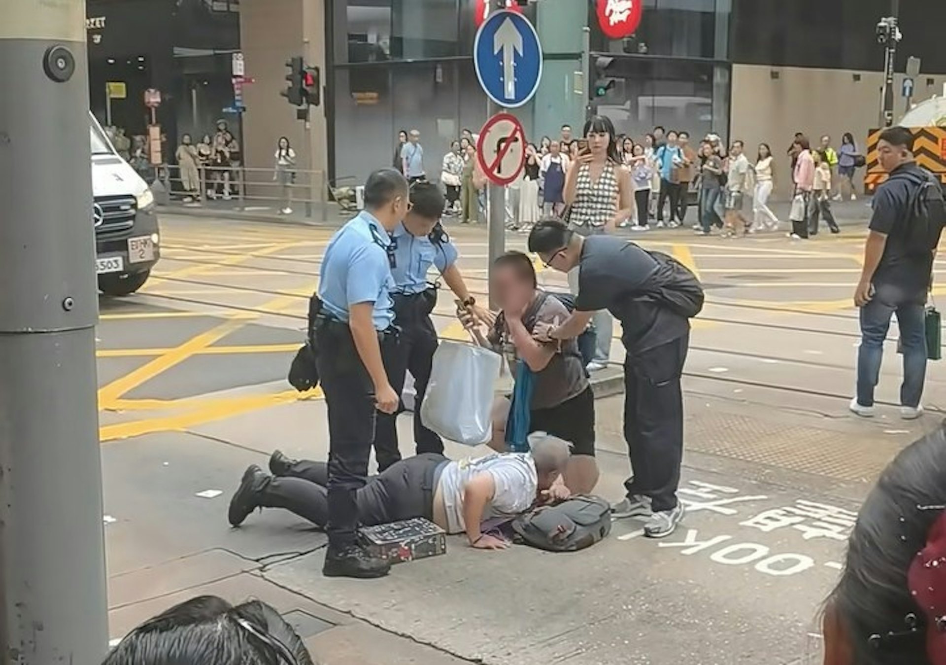 兩名男子疑在中環德輔道中與租庇利街交界,因身體碰撞爆發衝突,其中一名穿短褲、揹藍色背囊的男子,將另一名穿長褲的男子壓在地上。警員接報趕到現場,背囊放開長褲男後,用手掩住臉部。(小紅書/小红薯6AB38E3F)
