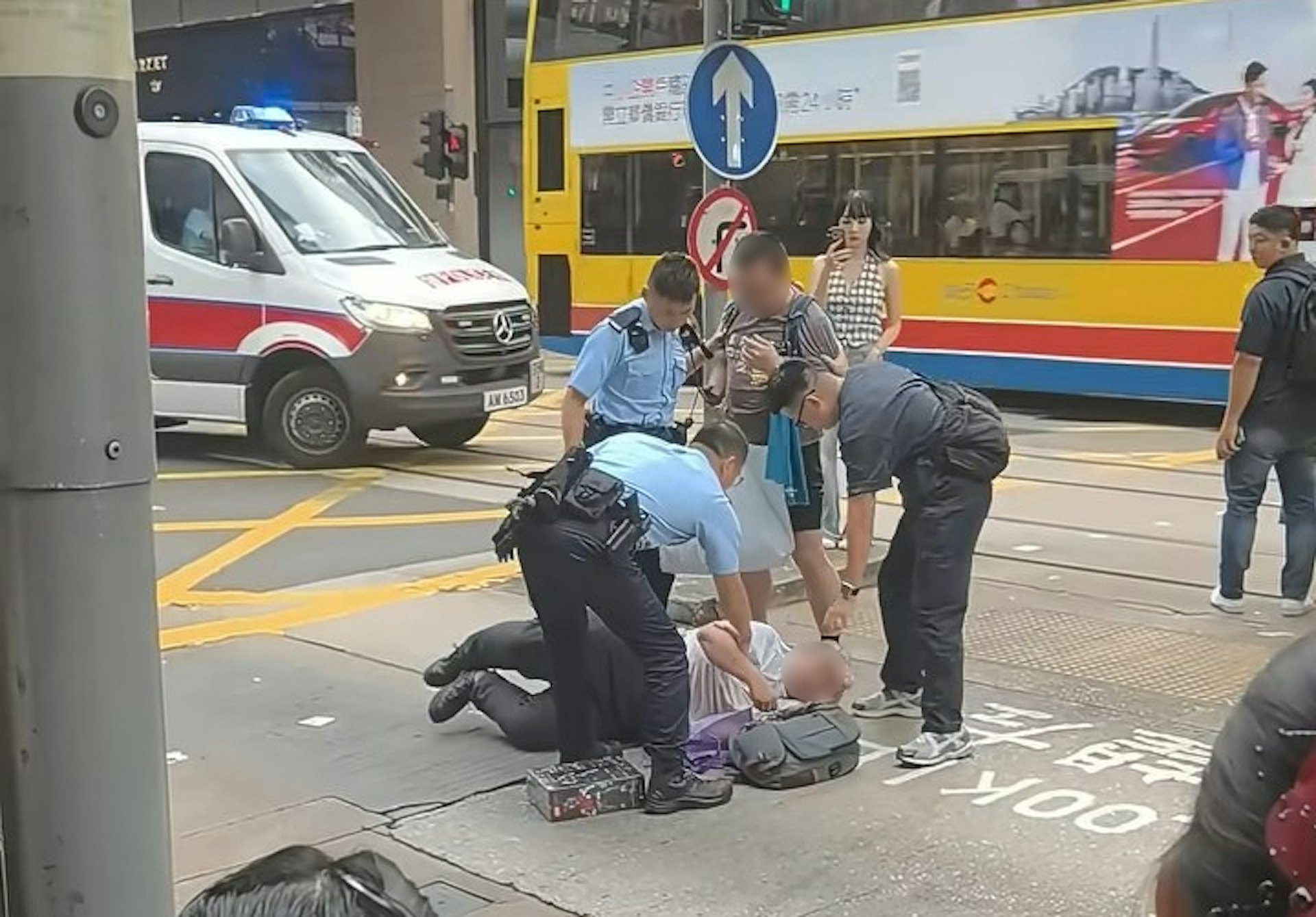 兩名男子疑在中環德輔道中與租庇利街交界,因身體碰撞爆發衝突,其中一名穿短褲、揹藍色背囊的男子,將另一名穿長褲的男子壓在地上。警員接報趕到現場,背囊男站起後,警員即查看仍伏在地上的長褲男情況。(小紅書/小红薯6AB38E3F)