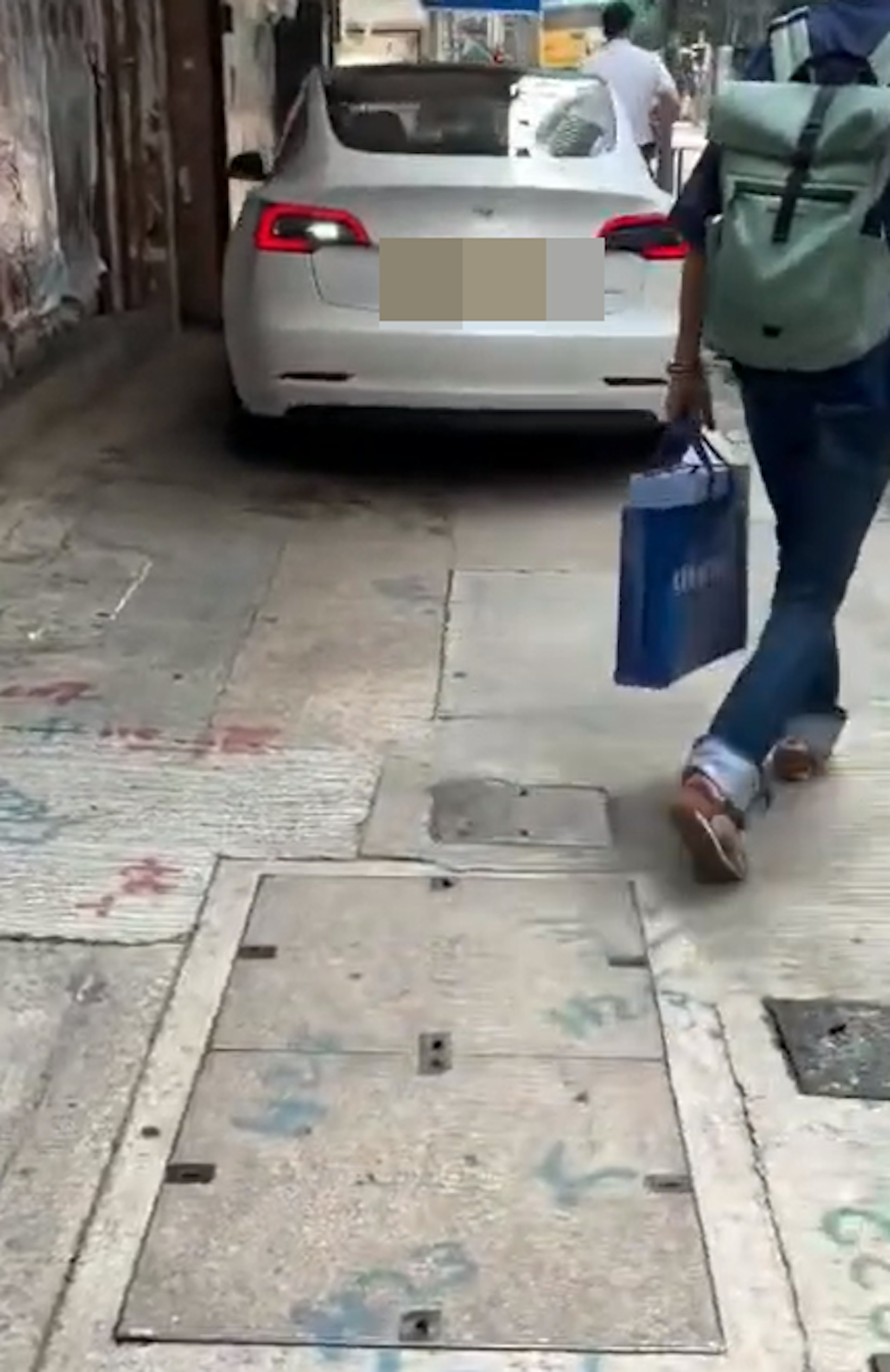 網上流傳事發一刻片段,可見涉事私家車為一輛白色Tesla,當時在一條狹窄的行人路上緩慢地倒車,附近亦有數名行人,情況相當驚險。(threads@cng1204)
