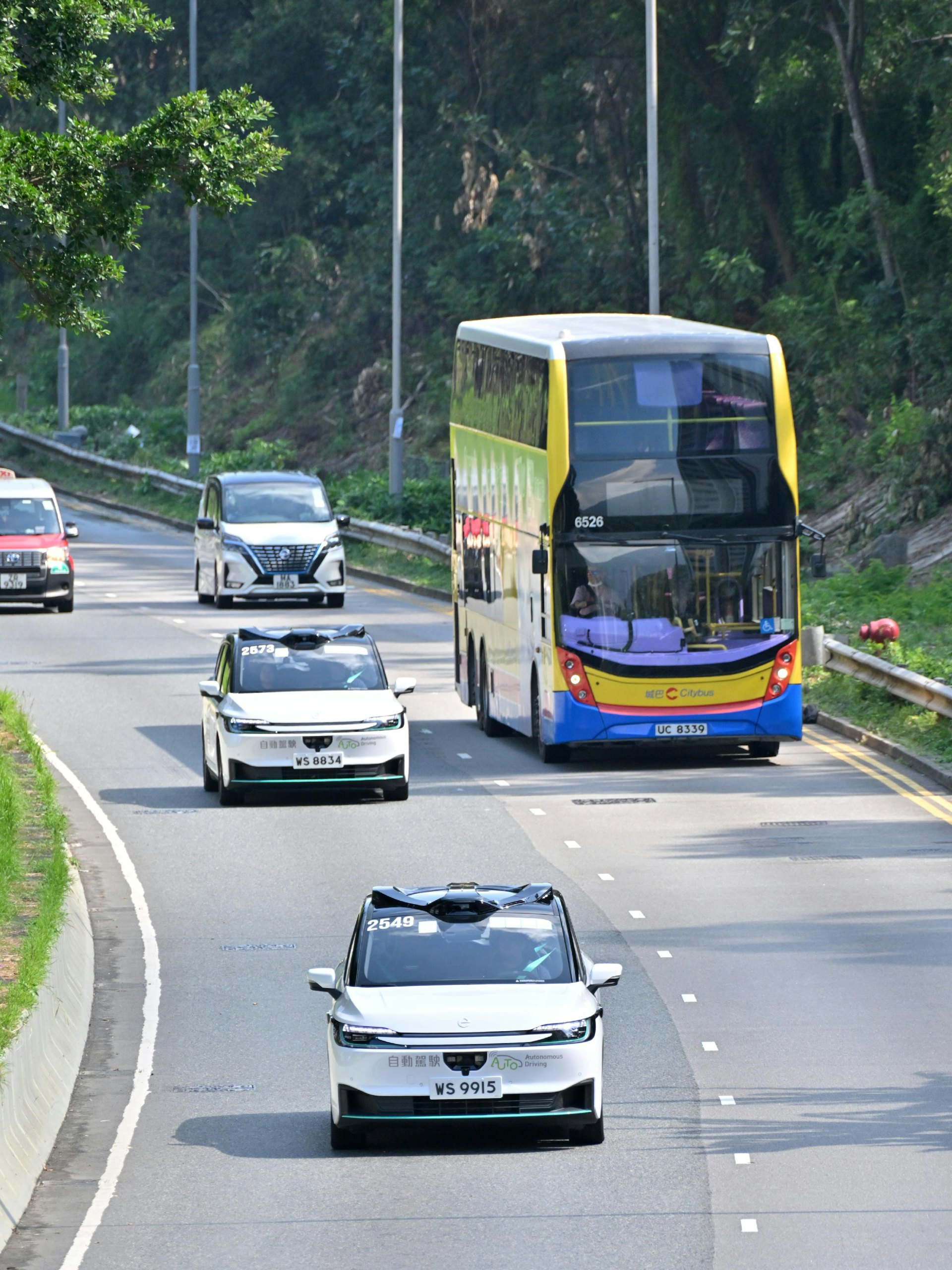 運輸署自動駕駛車輛應用促進工作組成員今日(10日)視察北大嶼山東涌的自動車測試項目,並試乘自動私家車。自動車在東涌市中心一帶駛過。(政府新聞網)