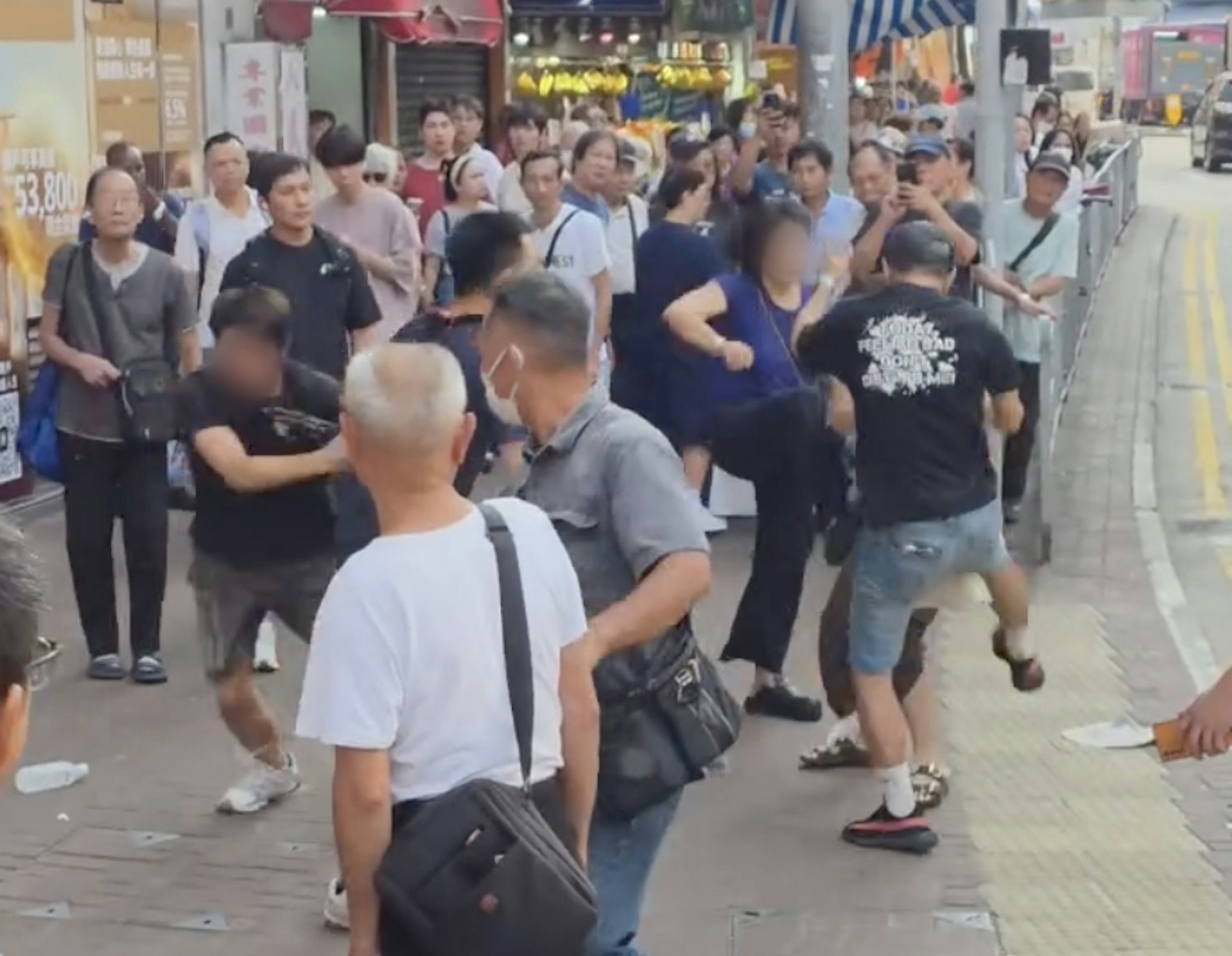 一名身穿深藍上衣的婦人加入戰團,與牛仔褲男一同伸腳踢向背心女。