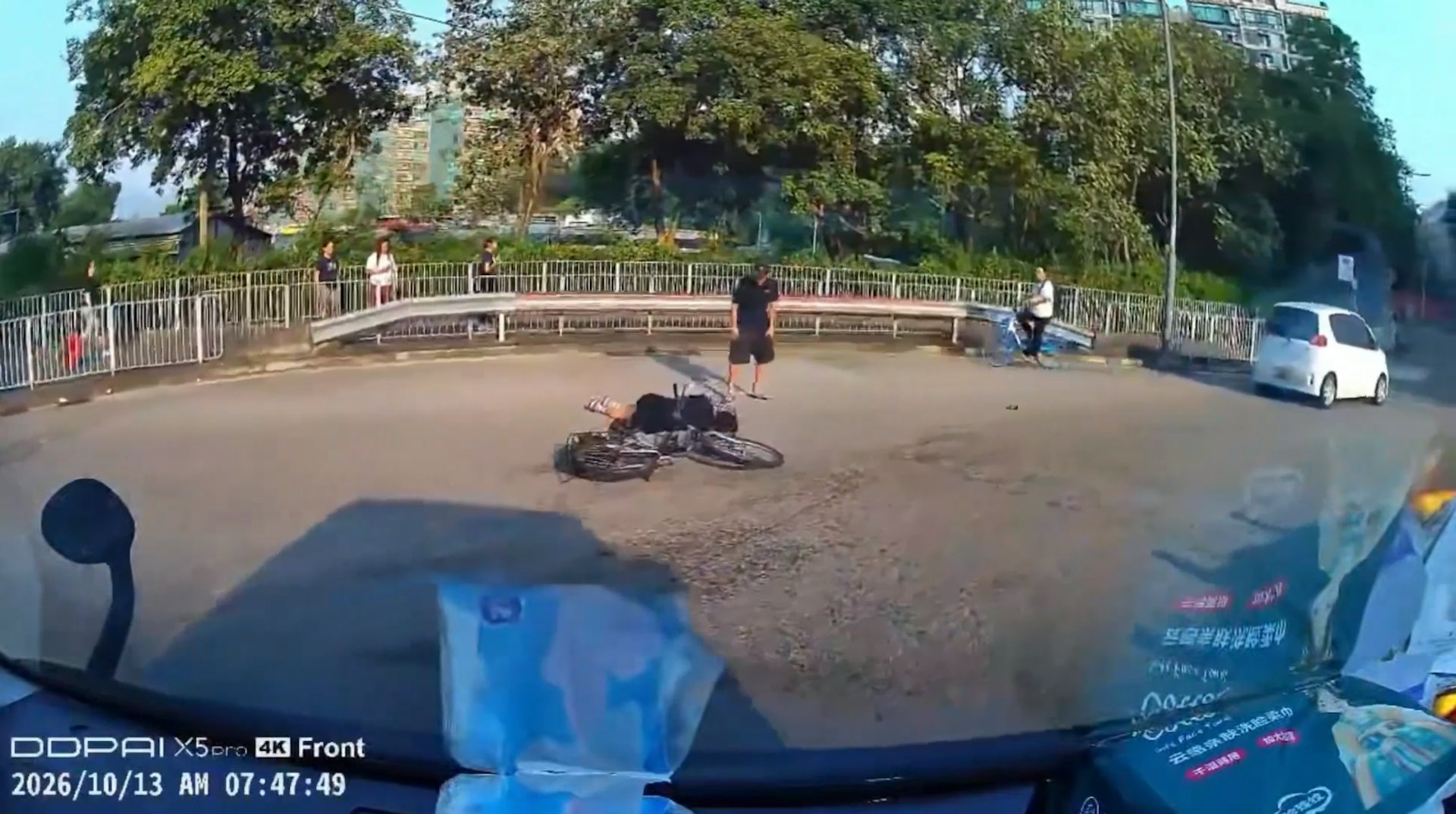 女事主連人帶車倒臥在迴旋處行車線中央;而在前方數米外,一輛懷疑涉事的白色私家車停在路旁,一名男子走近傷者身旁察看其傷勢及情況。