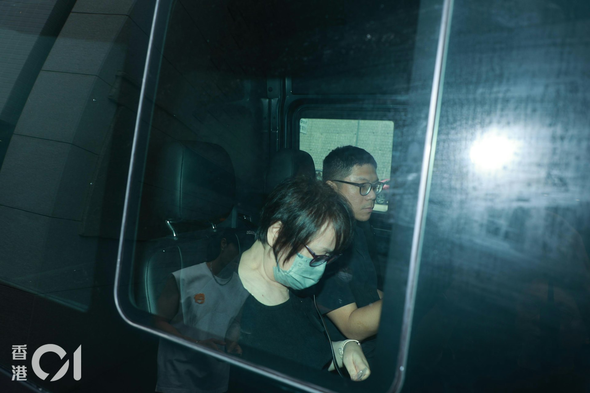 遗孀王心慰及男家属手持遗照登上灵车离开。