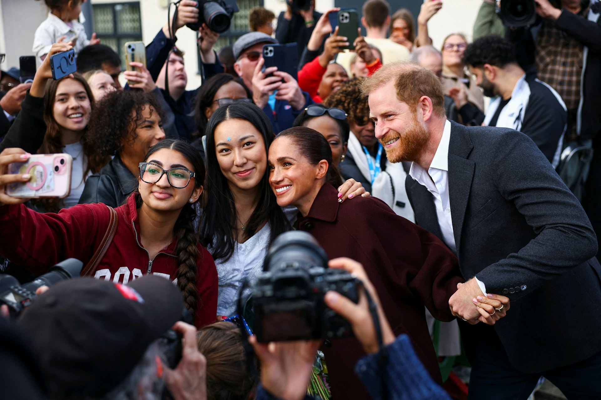 2026年10月15日,英国诺丁汉,哈里王子(Prince Harry)与夫人梅根(Meghan Markle)前往当地参观社区录音工作室。图为两人与现场民众合影。