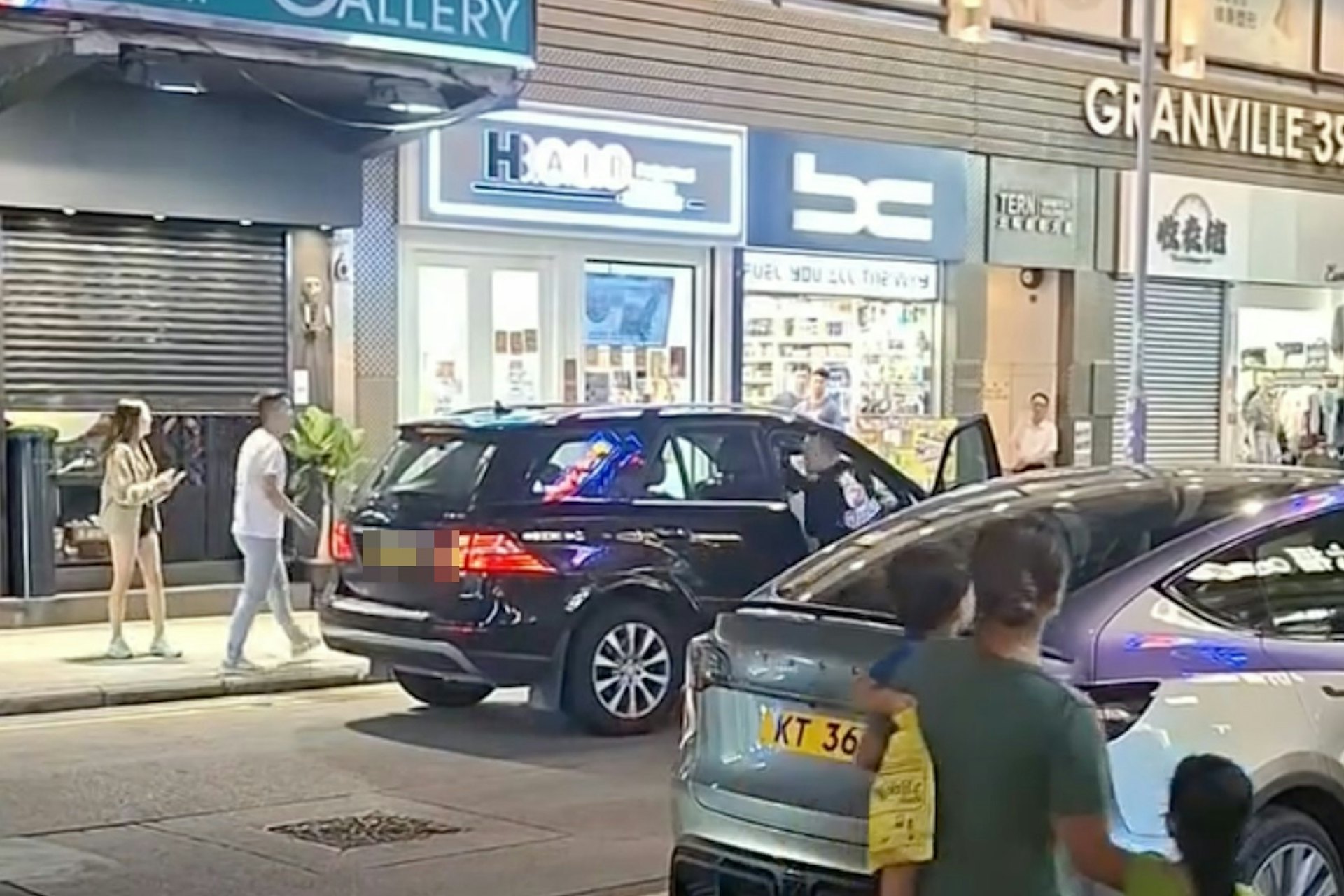 一名黑衣男走近一辆私家车座驾位置,司机位门打开,黑衣男未有停手不断向车内人士挥拳。