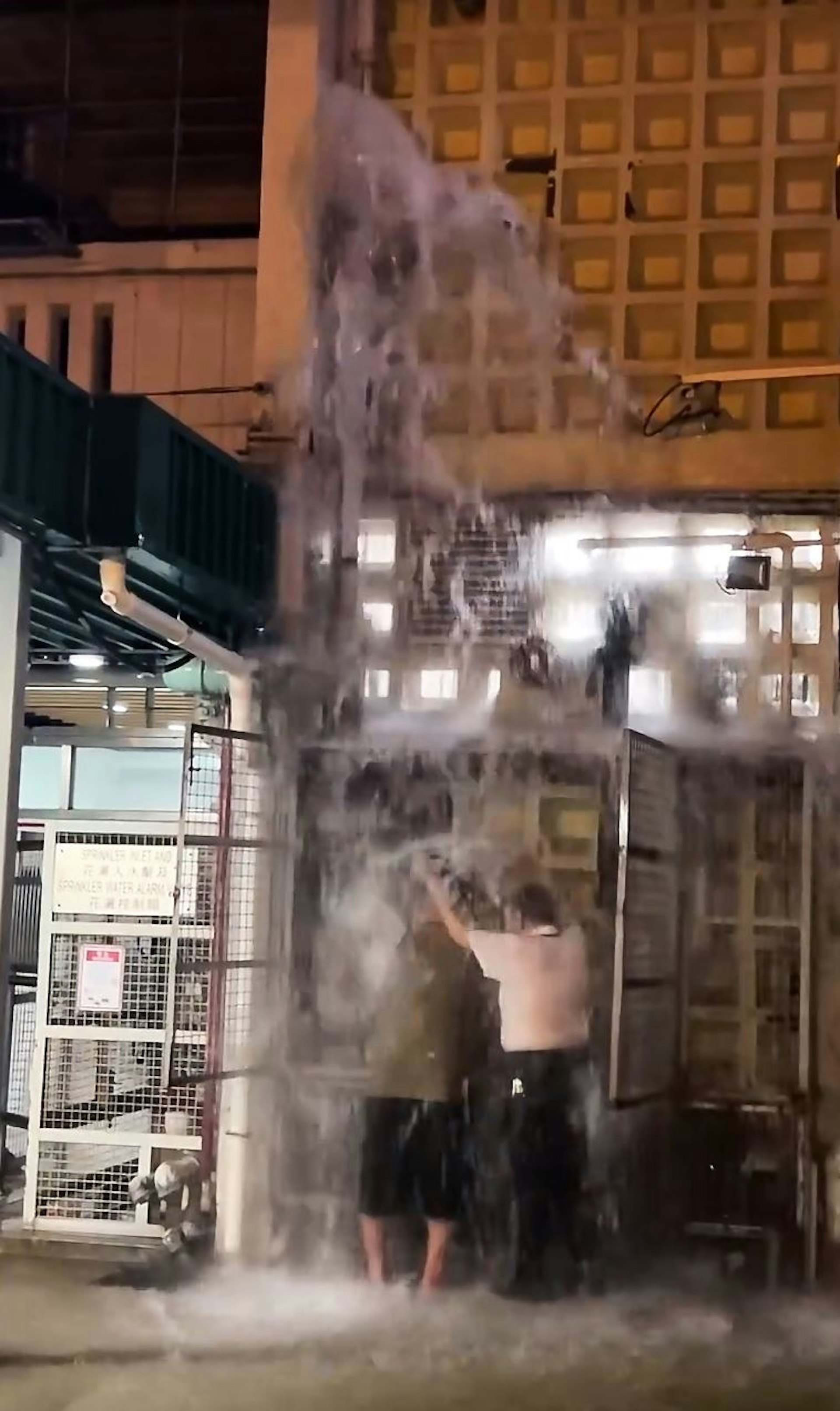 现场有2名男子站在水流附近,不排除是维修师傅和保安员,保安双手举起,手持物件,为师傅挡水,以便对方关上水掣。