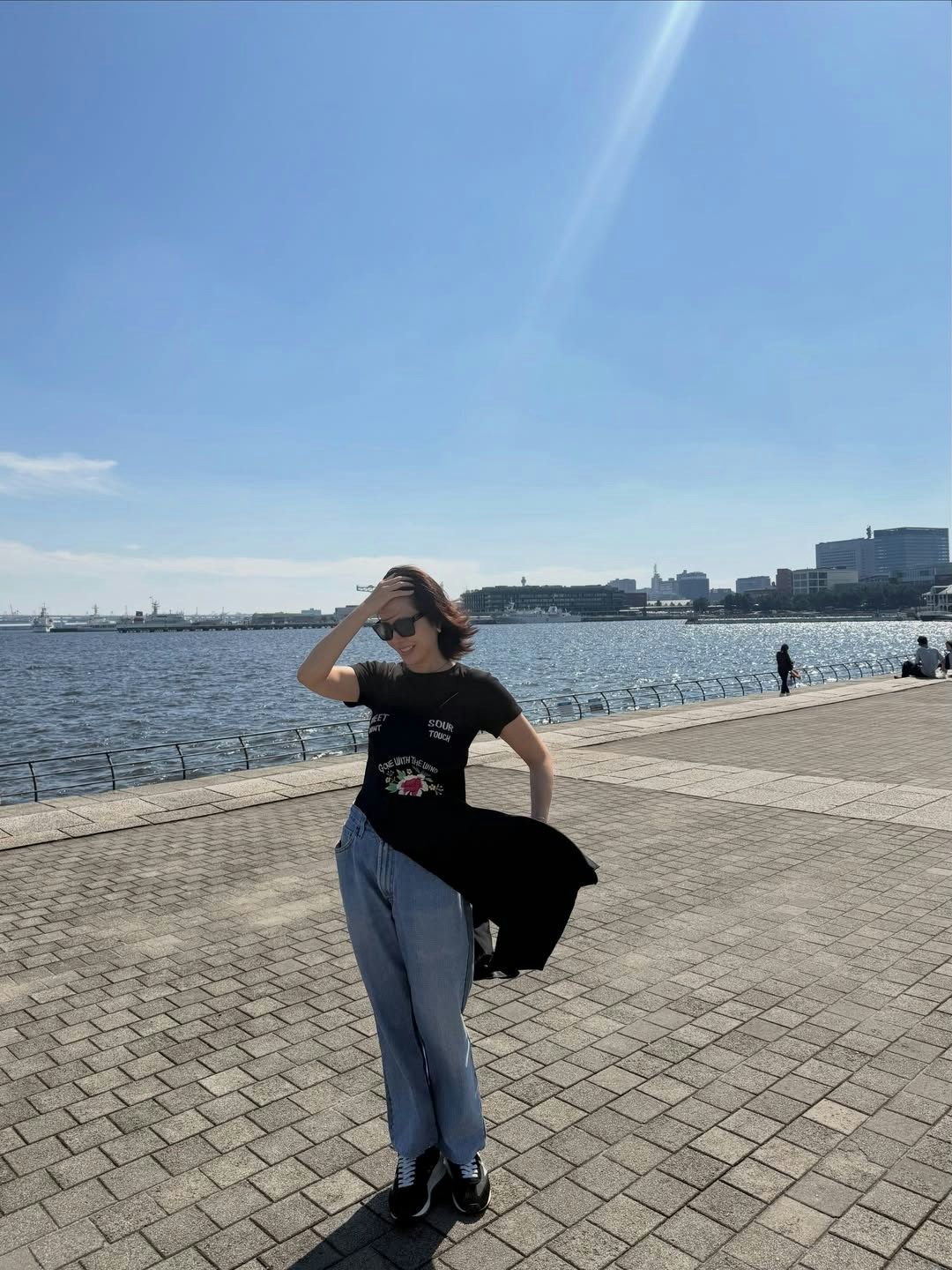 孙艺珍穿黑色上衣和牛仔裤站在海边